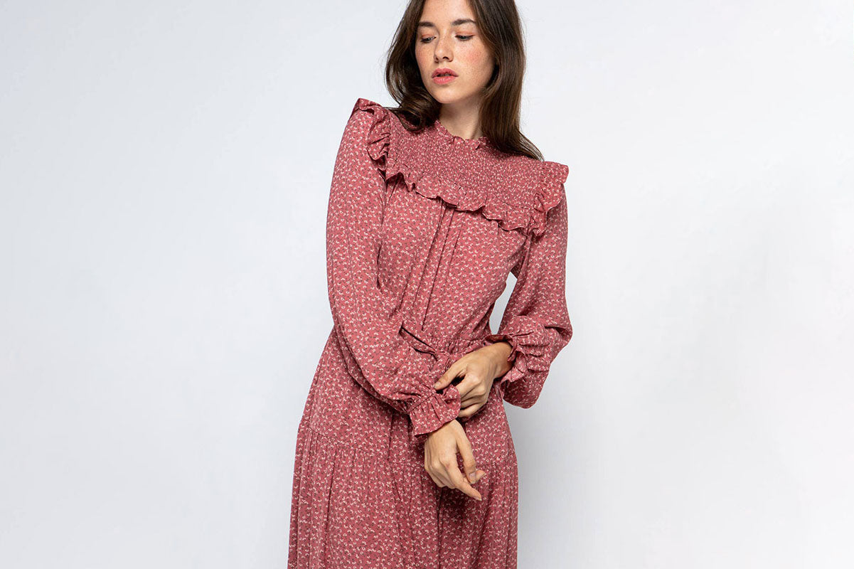Ruffled Prairie Dress in mauve with floral print, smocked yoke, bishop sleeves and tiered skirt ruffles on model against white background