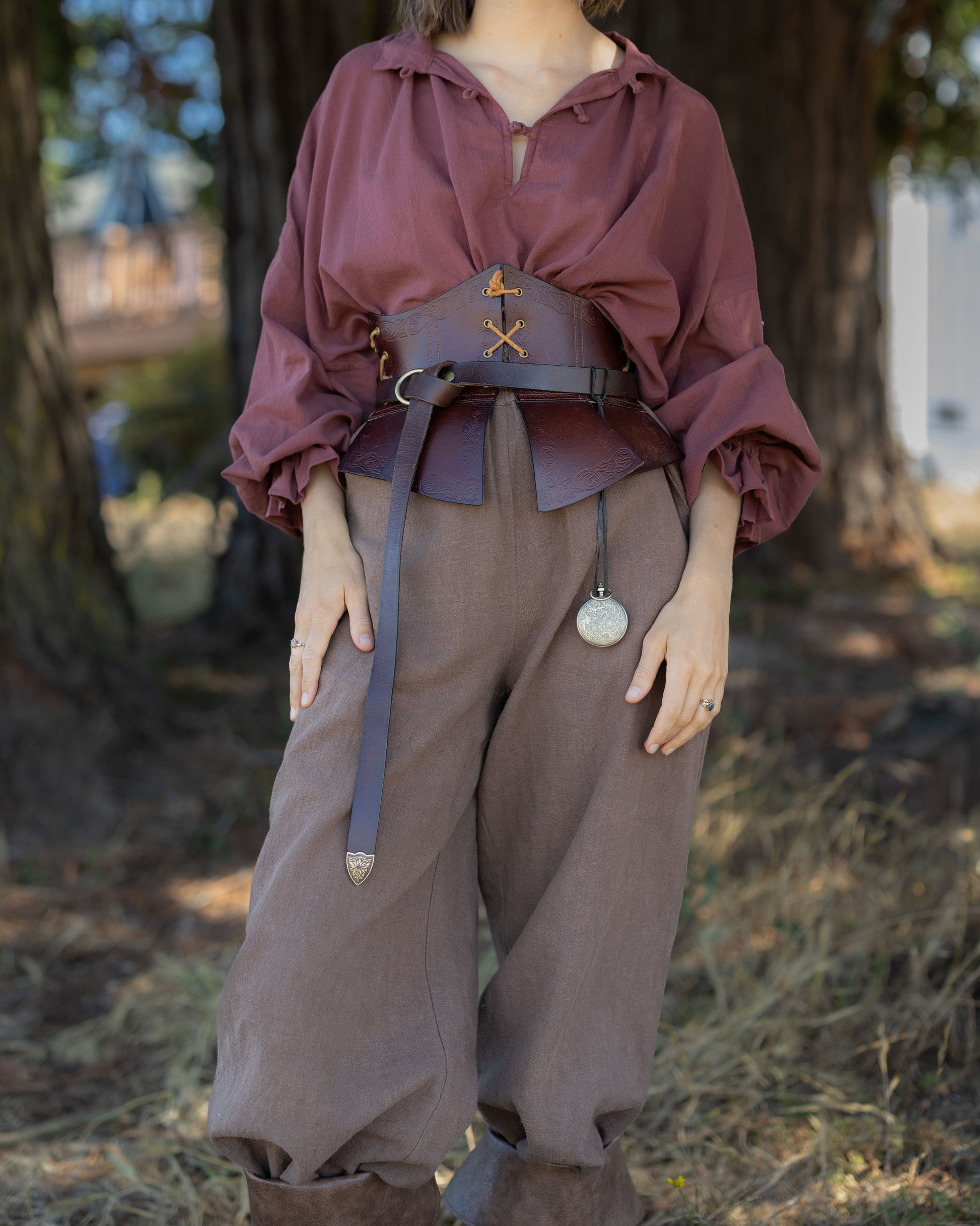 Person wearing a brown Darcy Shirt with billowing sleeves and a leather waist corset belt outdoors