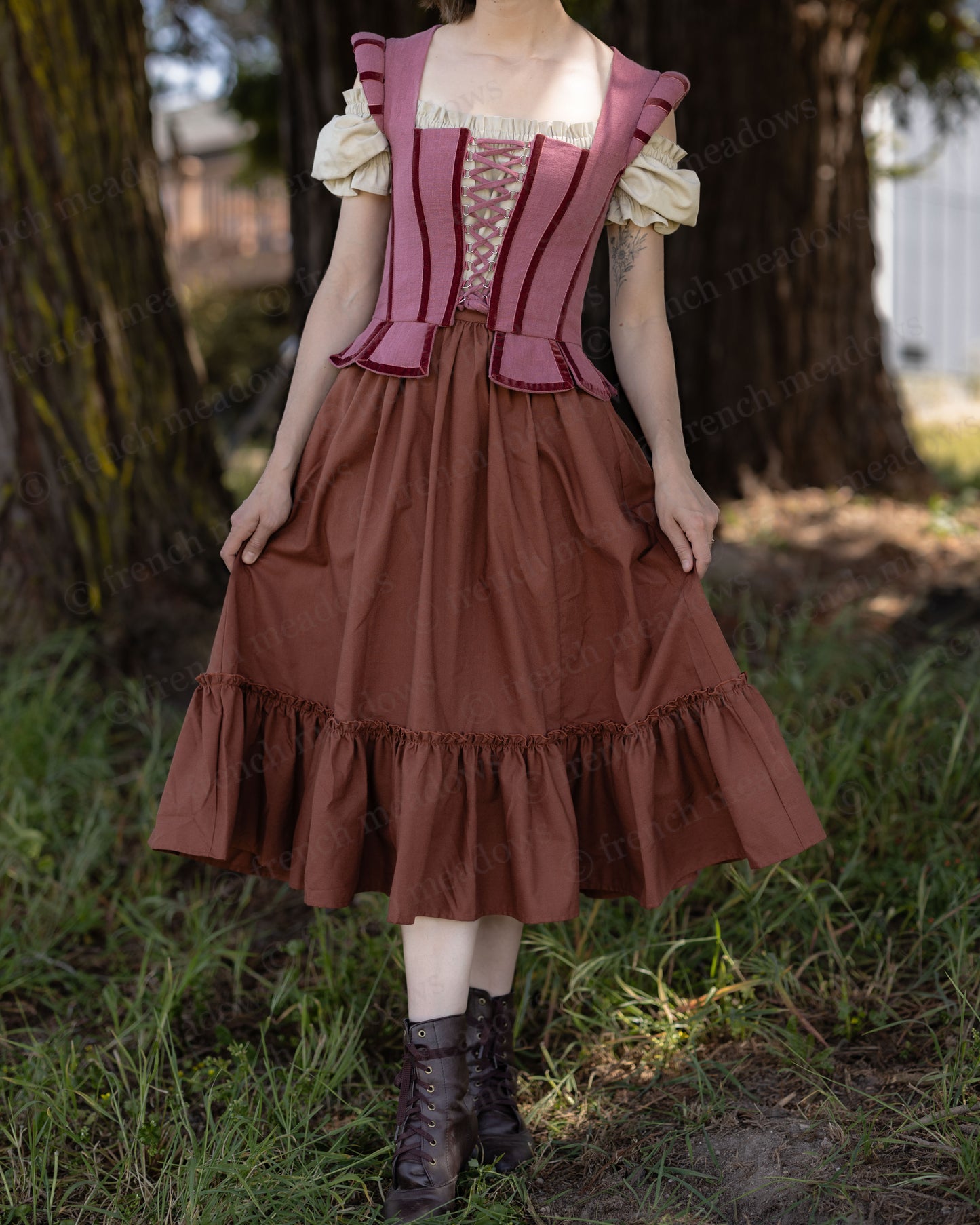 Woman wearing a rust linen midi skirt with ruffled hem and vintage-inspired corset top in outdoor setting