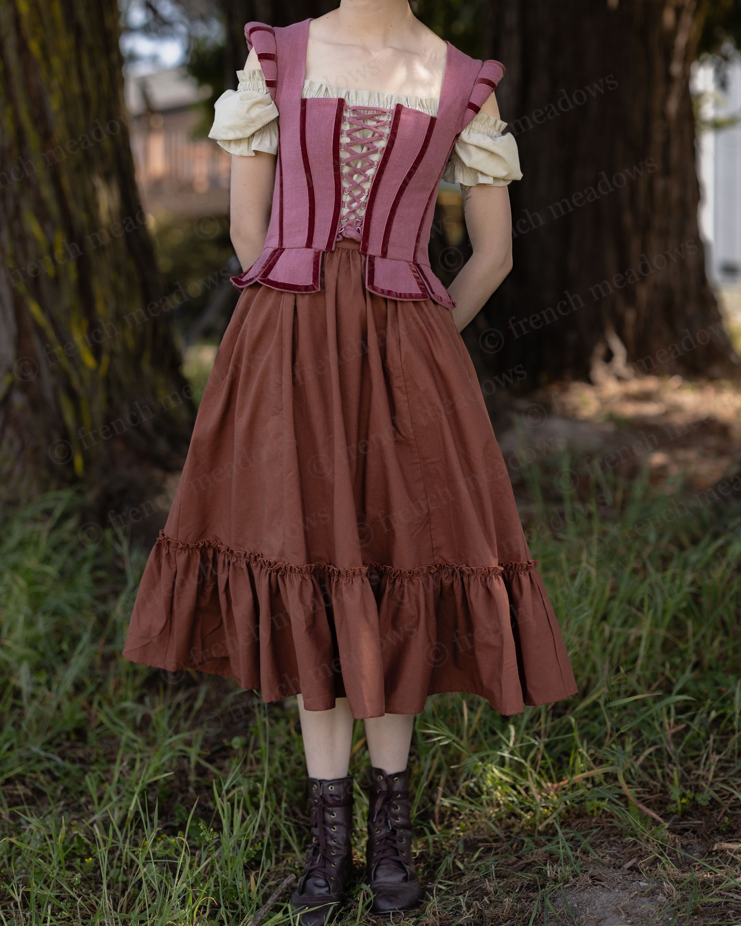 Woman wearing rust linen midi skirt with ruffled hem paired with corset and blouse outdoors on grass