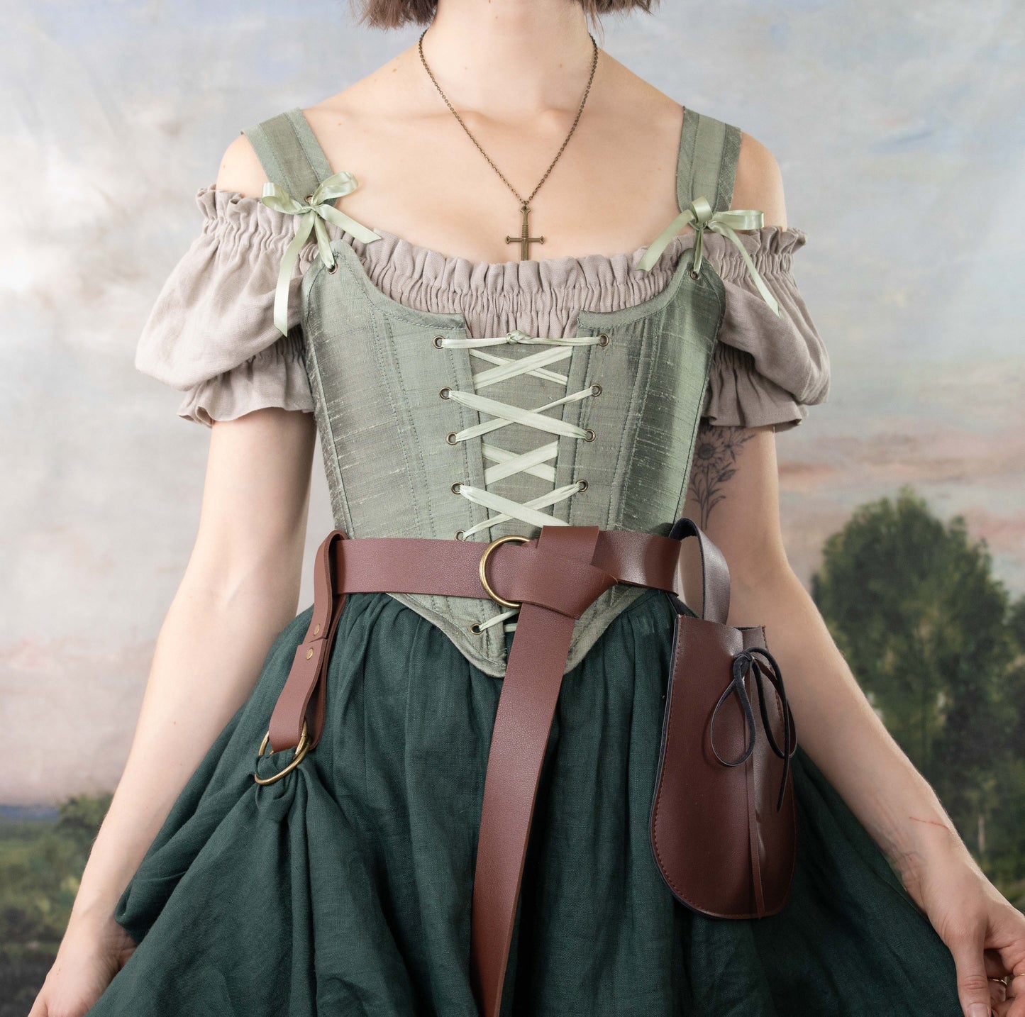 Woman wearing Handmade Sage Green Silk Corset over puffed sleeve top with brown leather belt and pouch outdoors