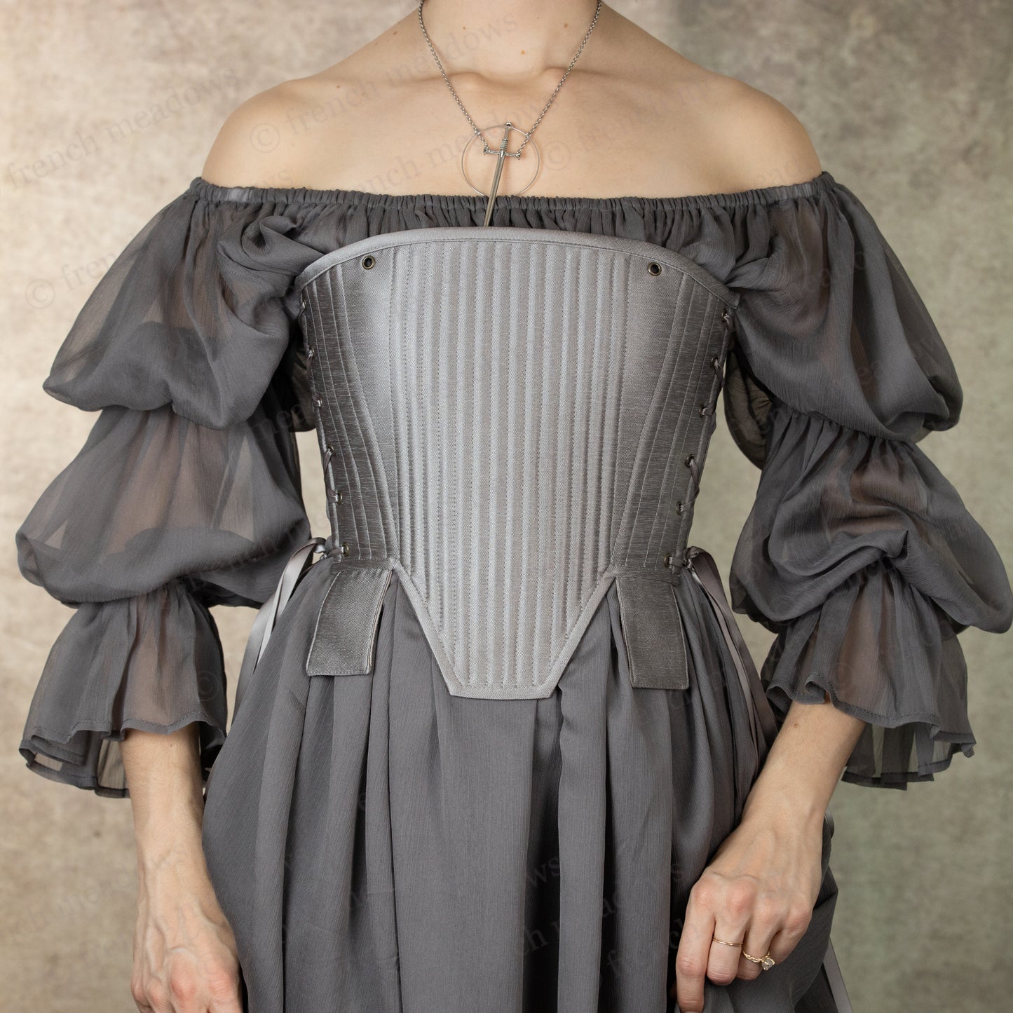Silver Tabbed Tudor Stays with off-shoulder grey puff sleeves and vertical boning, shown against textured backdrop, ornamental waist tabs