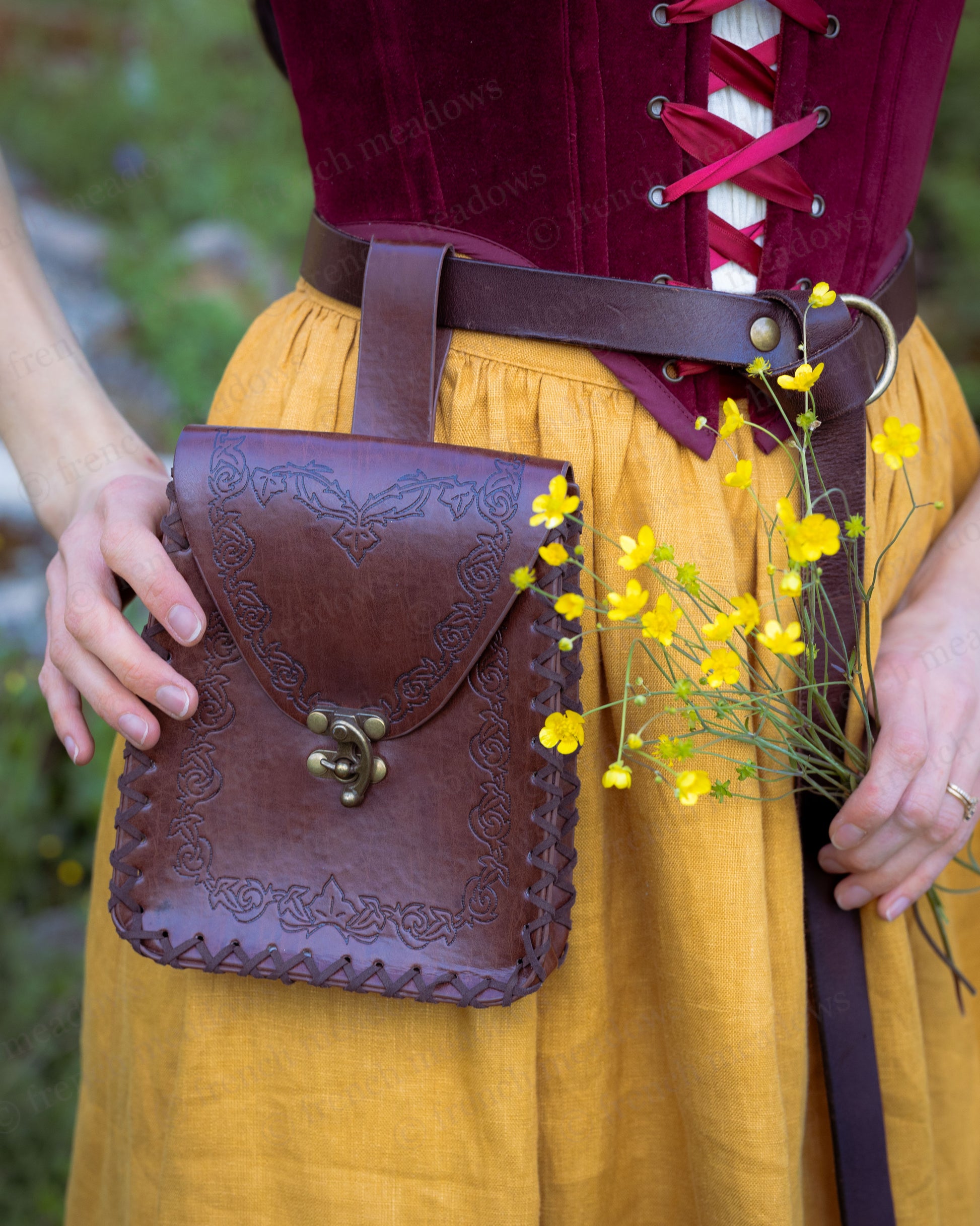 Elven Medieval Belt Pouch made of vegan leather with embossed design and clasp, worn on brown belt with yellow flowers.