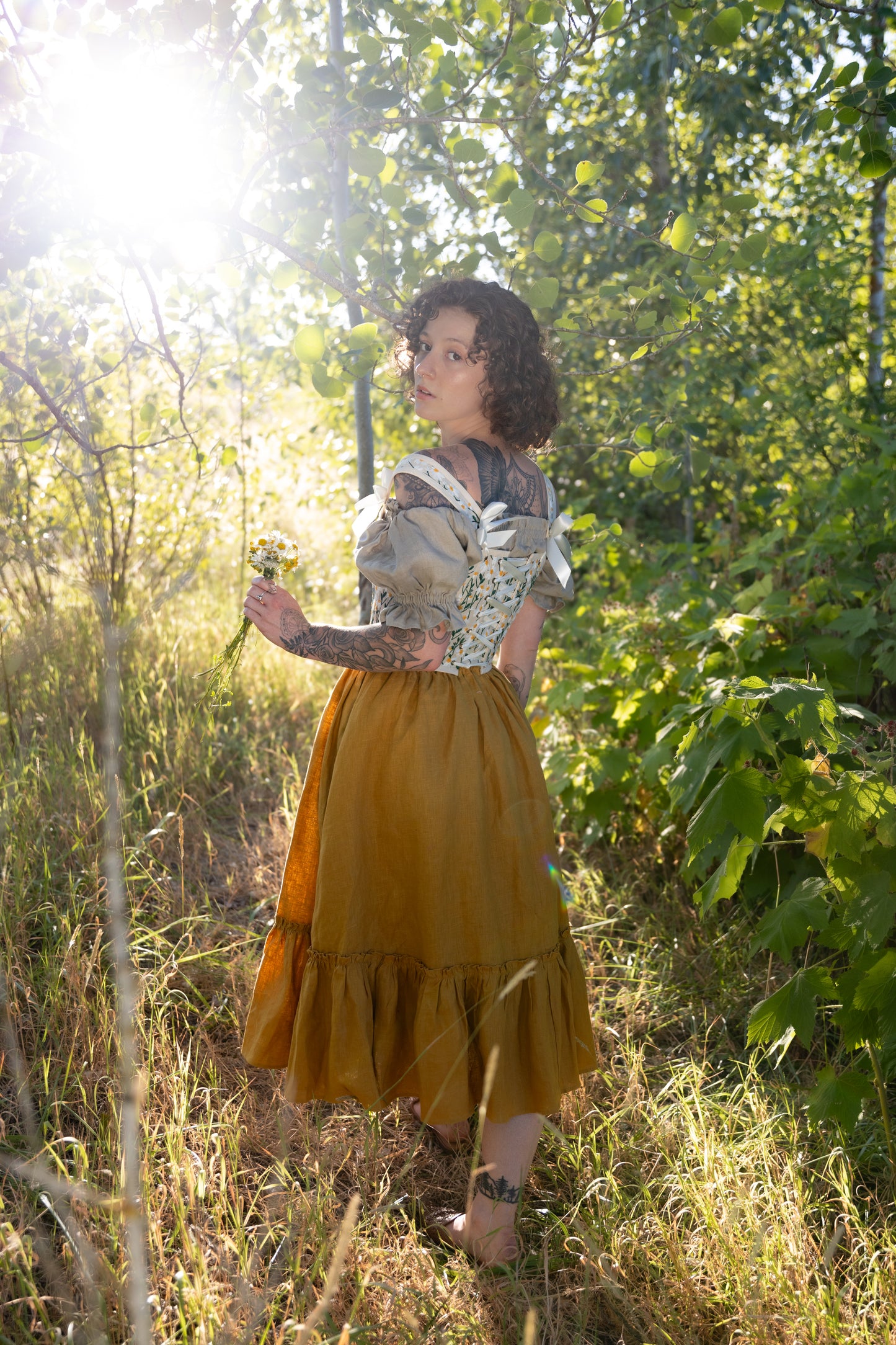 Embroidered Daisies Corset Top shown in sunlit forest setting, paired with flowing mustard skirt, highlighting floral details
