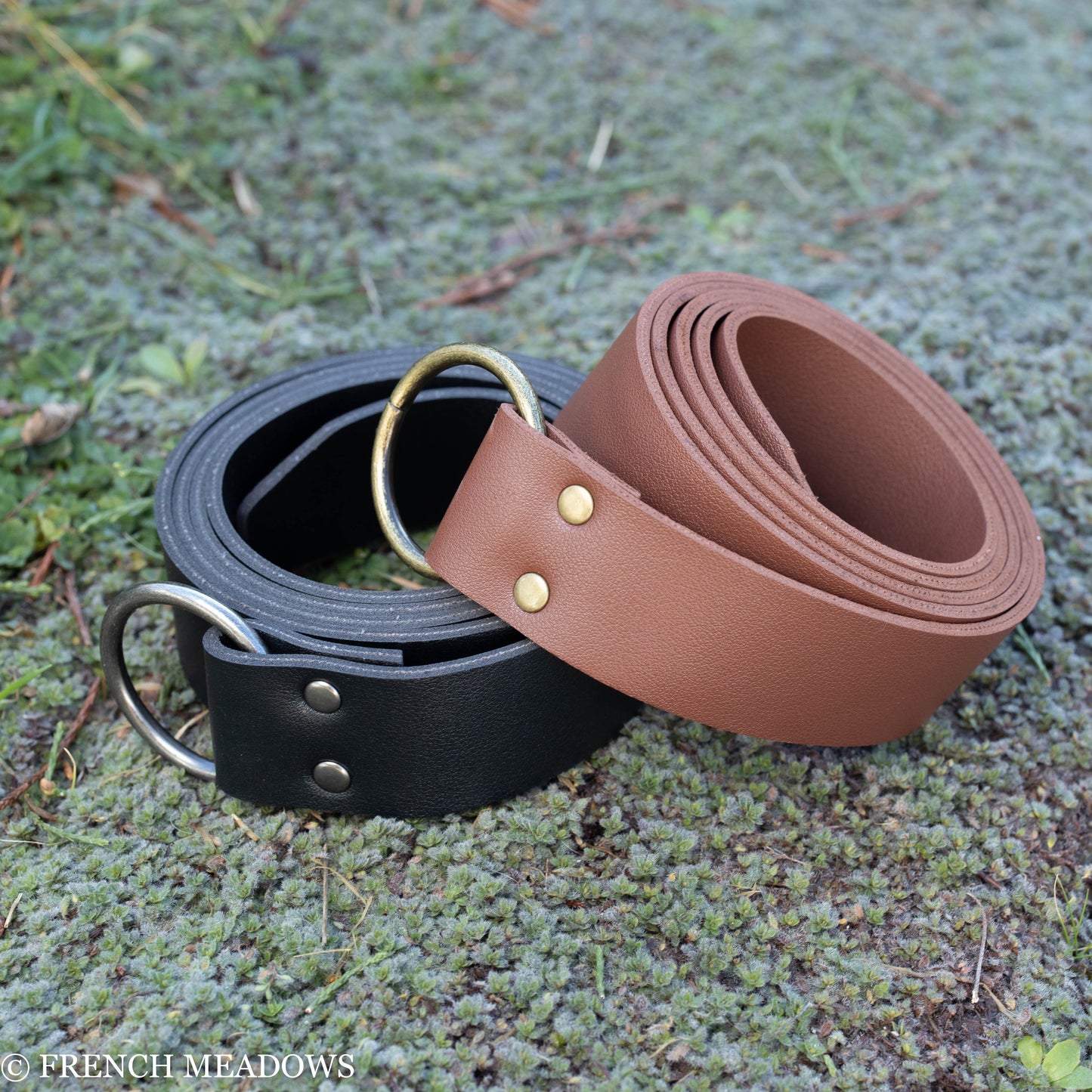 Vegan Leather Renaissance Belt in brown and black with metal D-rings and rivets, displayed on mossy ground