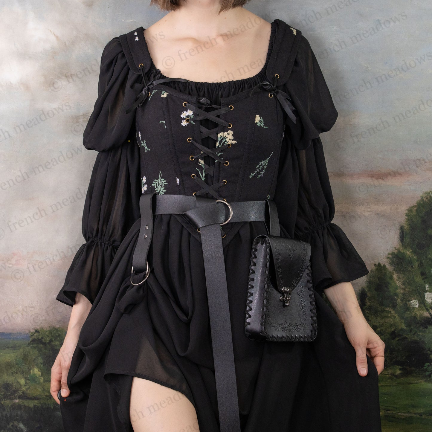 Elven Medieval Belt Pouch in black vegan leather with intricate scroll design, hanging from belt of gothic dress with embroidered details