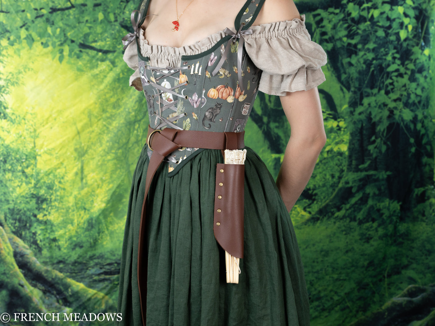 Fan Holster in brown leather attached to renaissance dress with decorative silver buckle against forest background