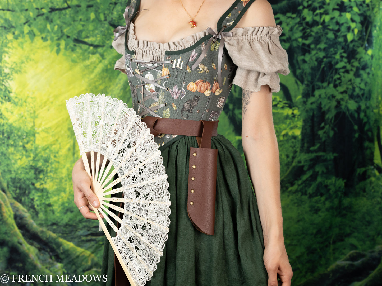 Fan Holster in brown vegan leather worn with renaissance dress, displaying white lace fan against forest backdrop