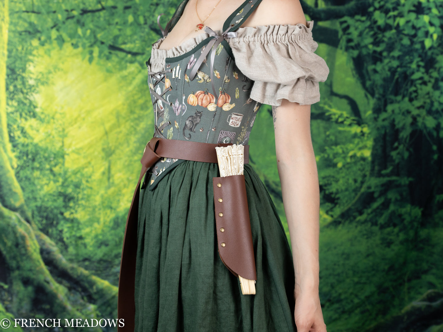 Brown leather Fan Holster attached to renaissance dress with floral bodice and green skirt, displayed against forest background