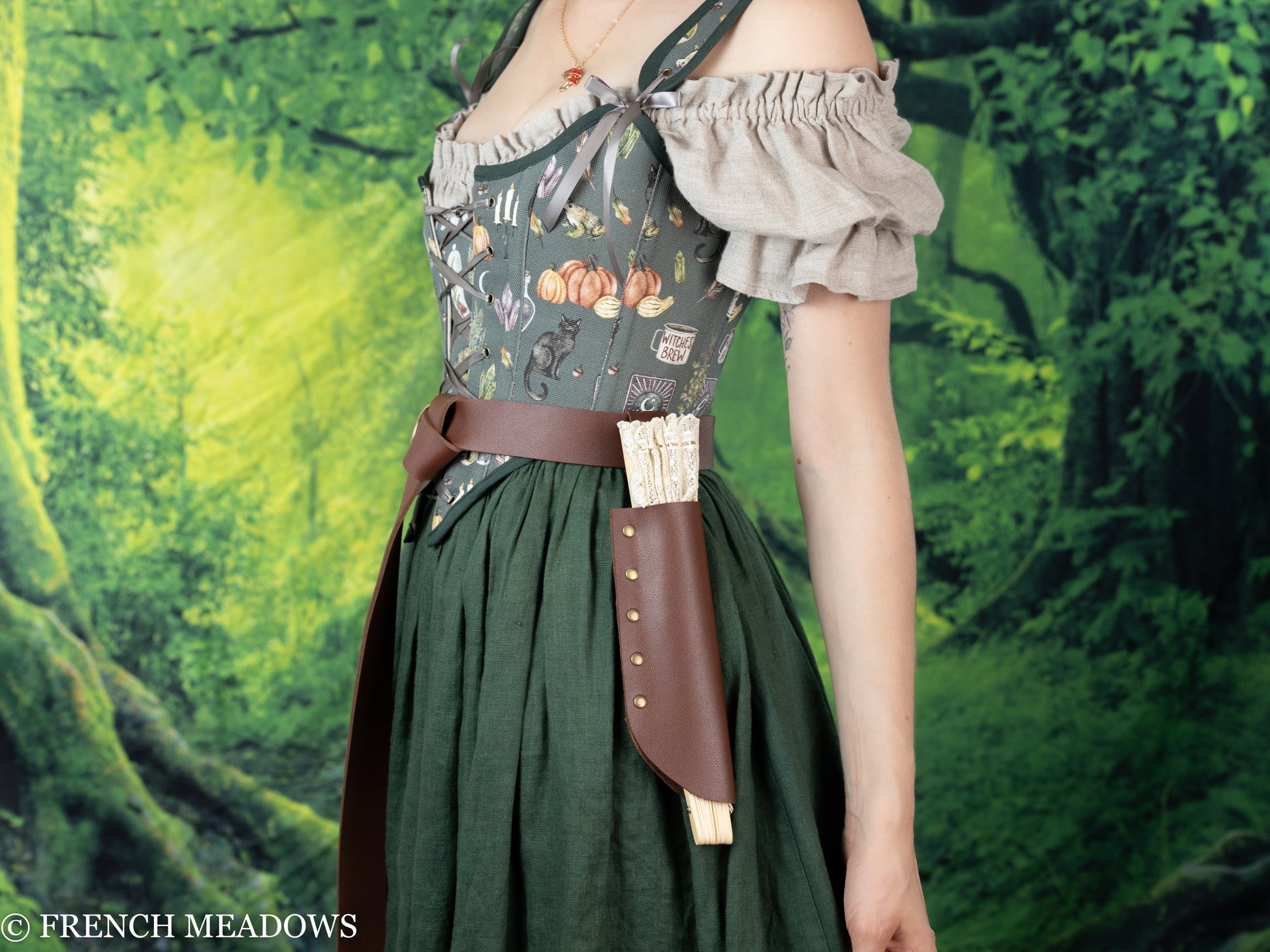 Brown leather Fan Holster attached to renaissance dress with floral bodice and green skirt, displayed against forest background