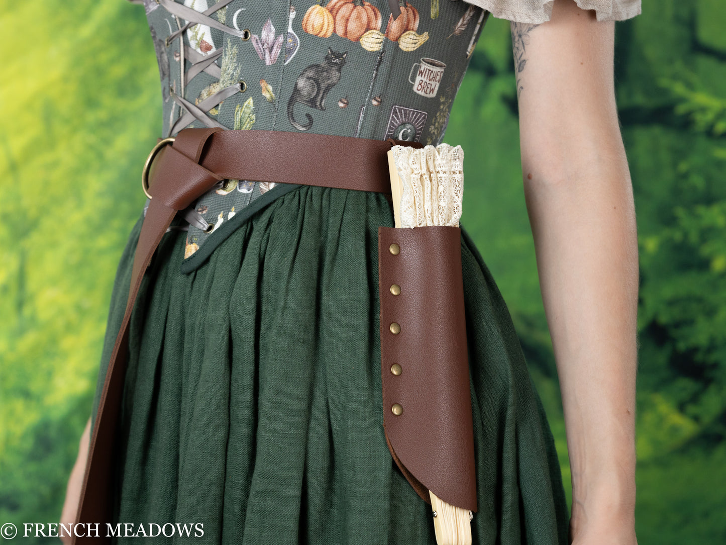 Brown leather Fan Holster with decorative handle attached to belt over green renaissance dress with floral pattern bodice