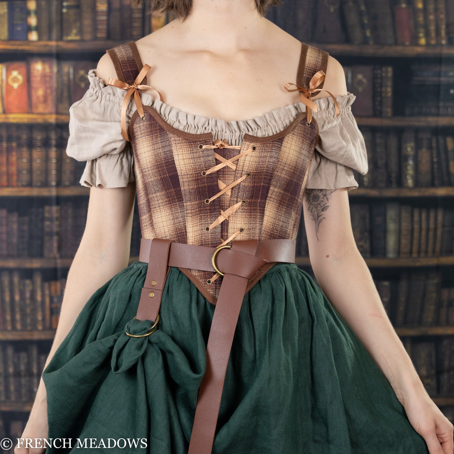 Person wearing Vegan Leather Renaissance Belt with brown plaid bodice and green skirt in library setting