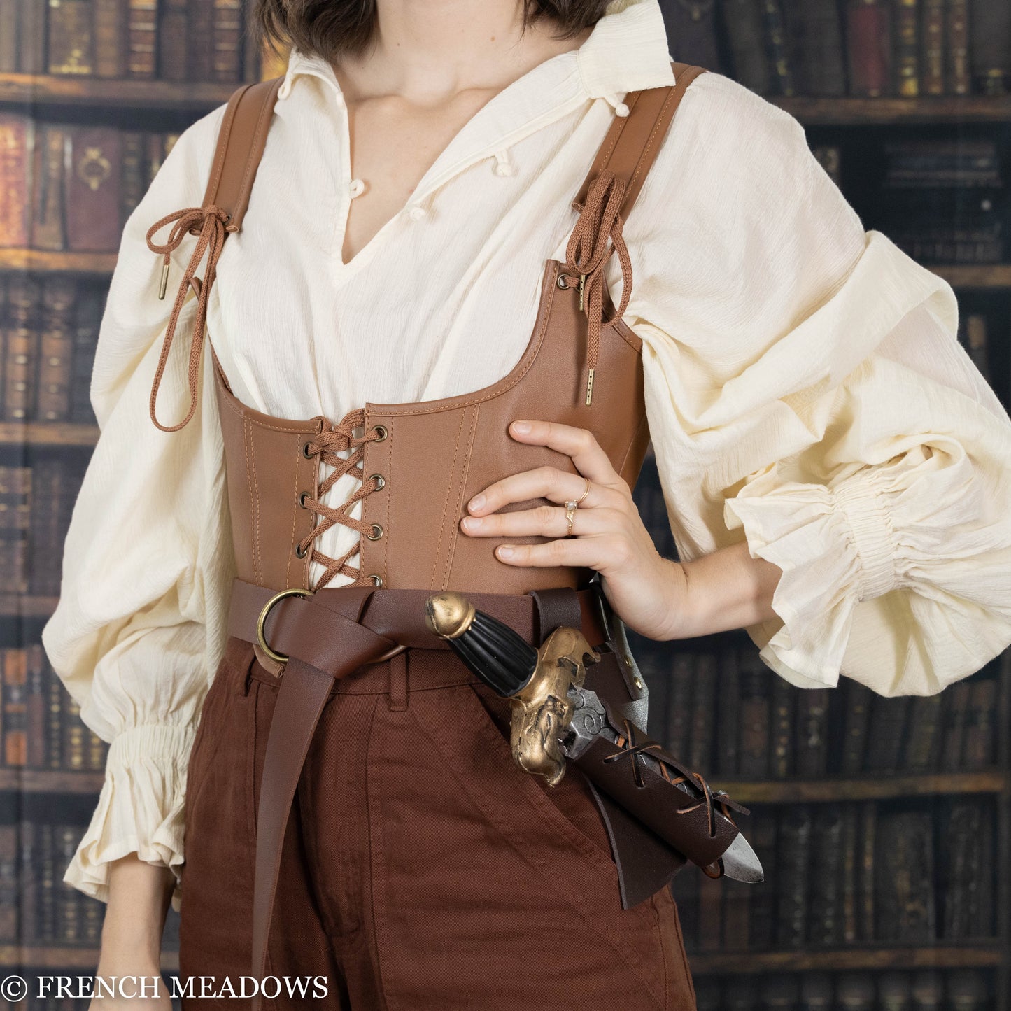 Brown vegan leather sword scabbard on belt, displayed with renaissance-style outfit against library background