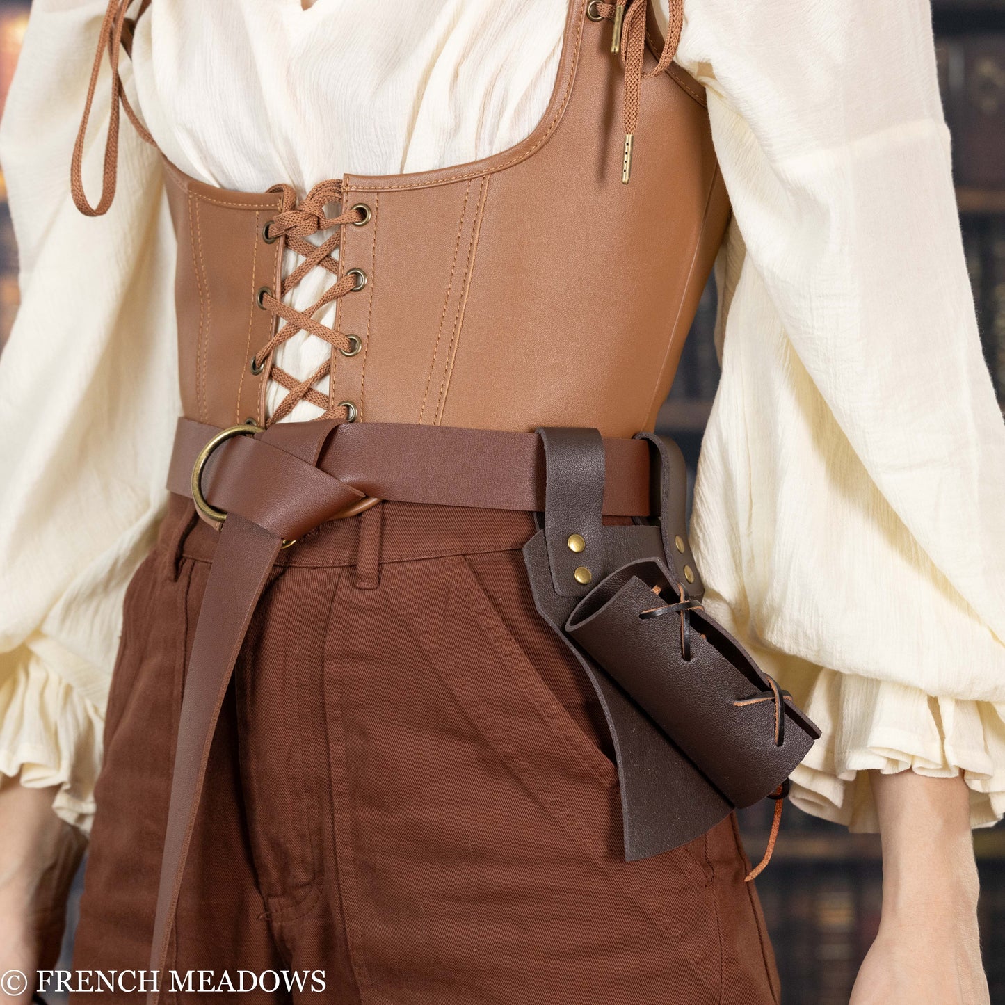 Brown leather sword scabbard attached to belt, shown with medieval-style costume featuring corset and white blouse