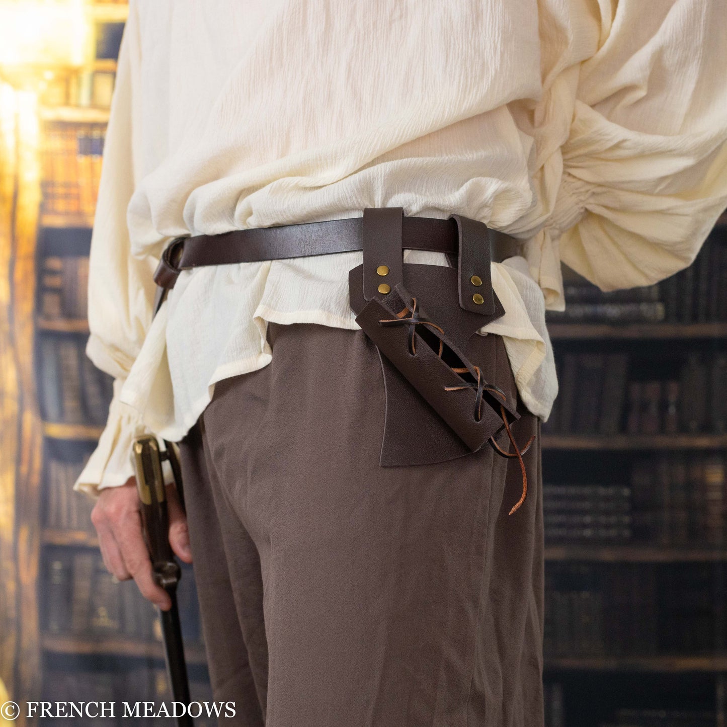 Brown leather sword scabbard with adjustable lacing worn on belt, displayed against medieval costume attire