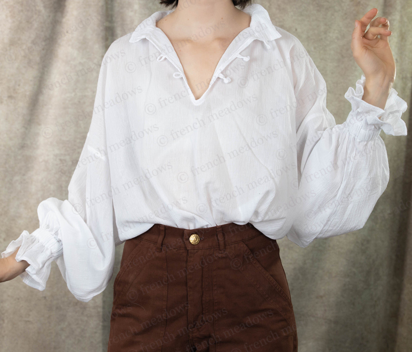 Darcy Shirt: Ivory cotton poet blouse with billowing sleeves and knotted button closure, styled with brown pants