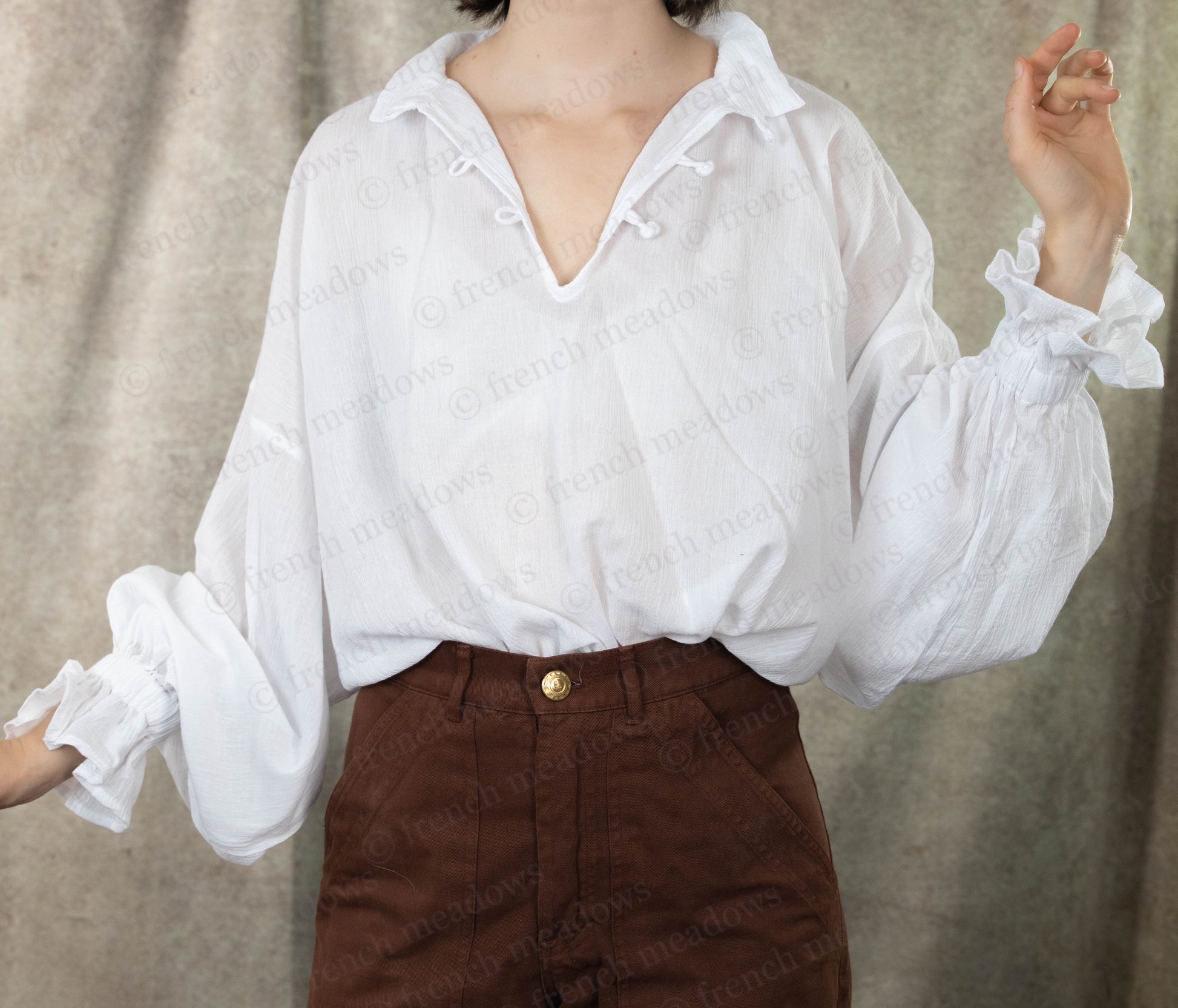 Darcy Shirt: Ivory cotton poet blouse with billowing sleeves and knotted button closure, styled with brown pants