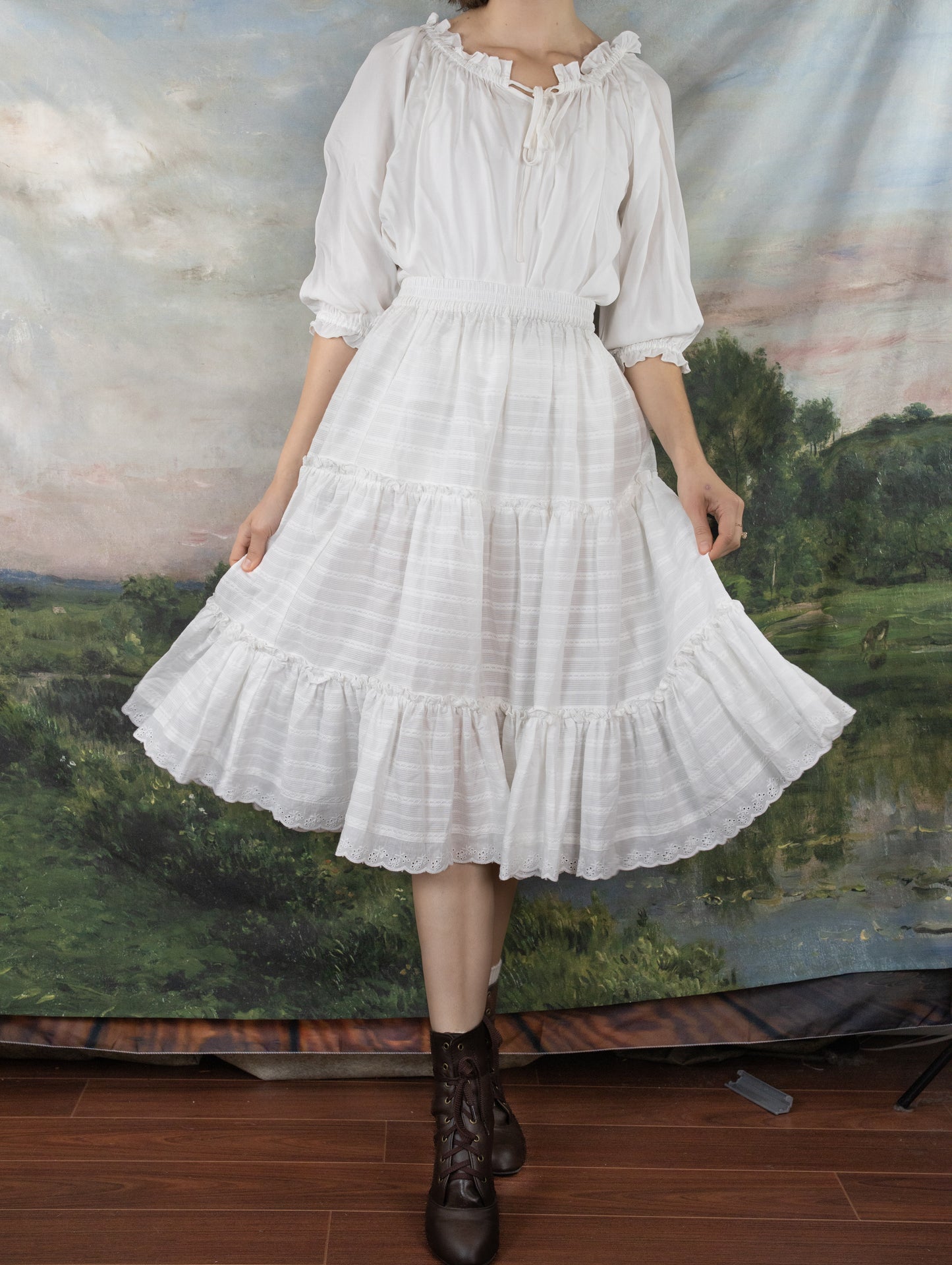 White Cotton Petticoat with tiered ruffles and lace trim against pastoral backdrop, shown with brown lace-up boots