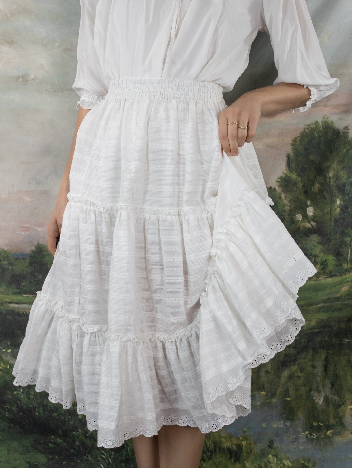 White Cotton Petticoat with tiered ruffles and lace trim shown against pastoral backdrop, held to display full skirt movement
