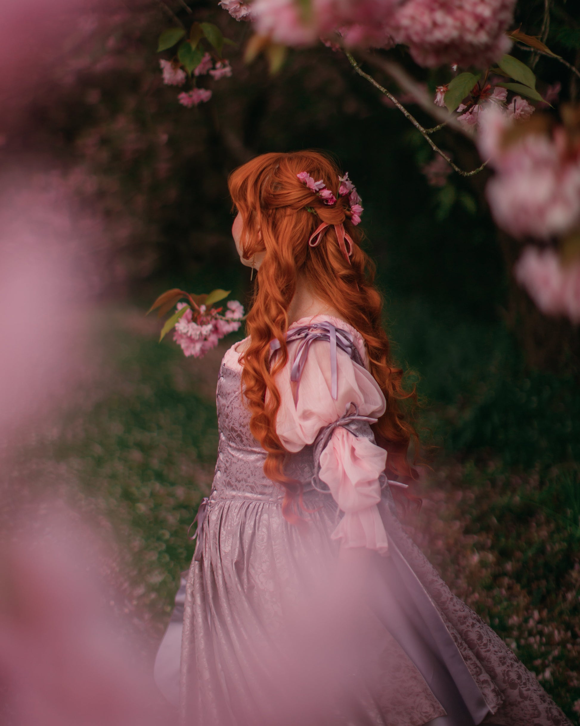Lavender Floral Satin Corset Dress worn by woman in garden, featuring lace-up bodice and delicate bow shoulder straps.