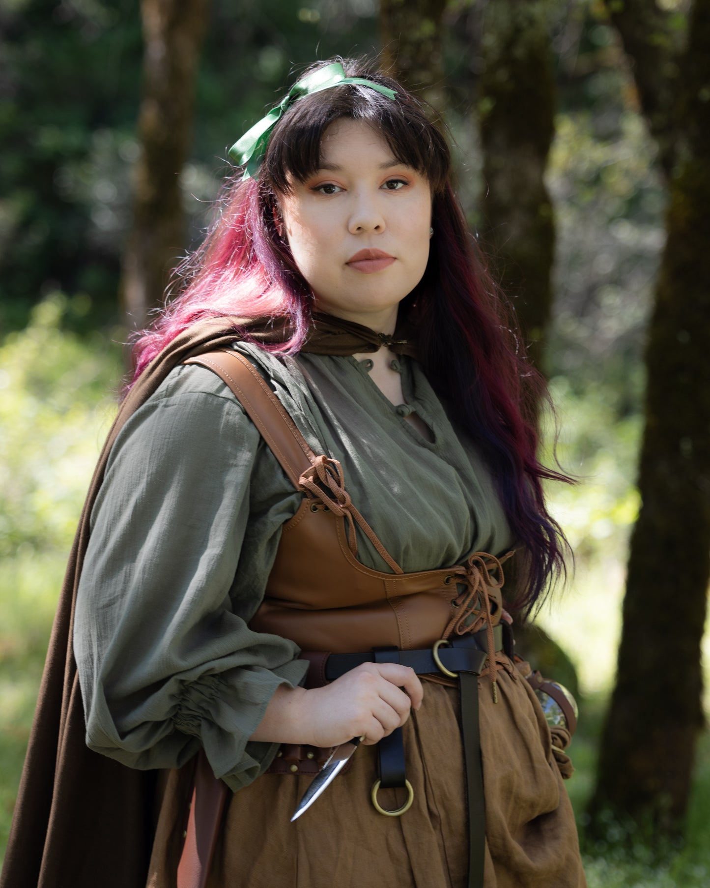 Woman wearing the Darcy Shirt with billowing sleeves and knotted neckline in a forest setting.