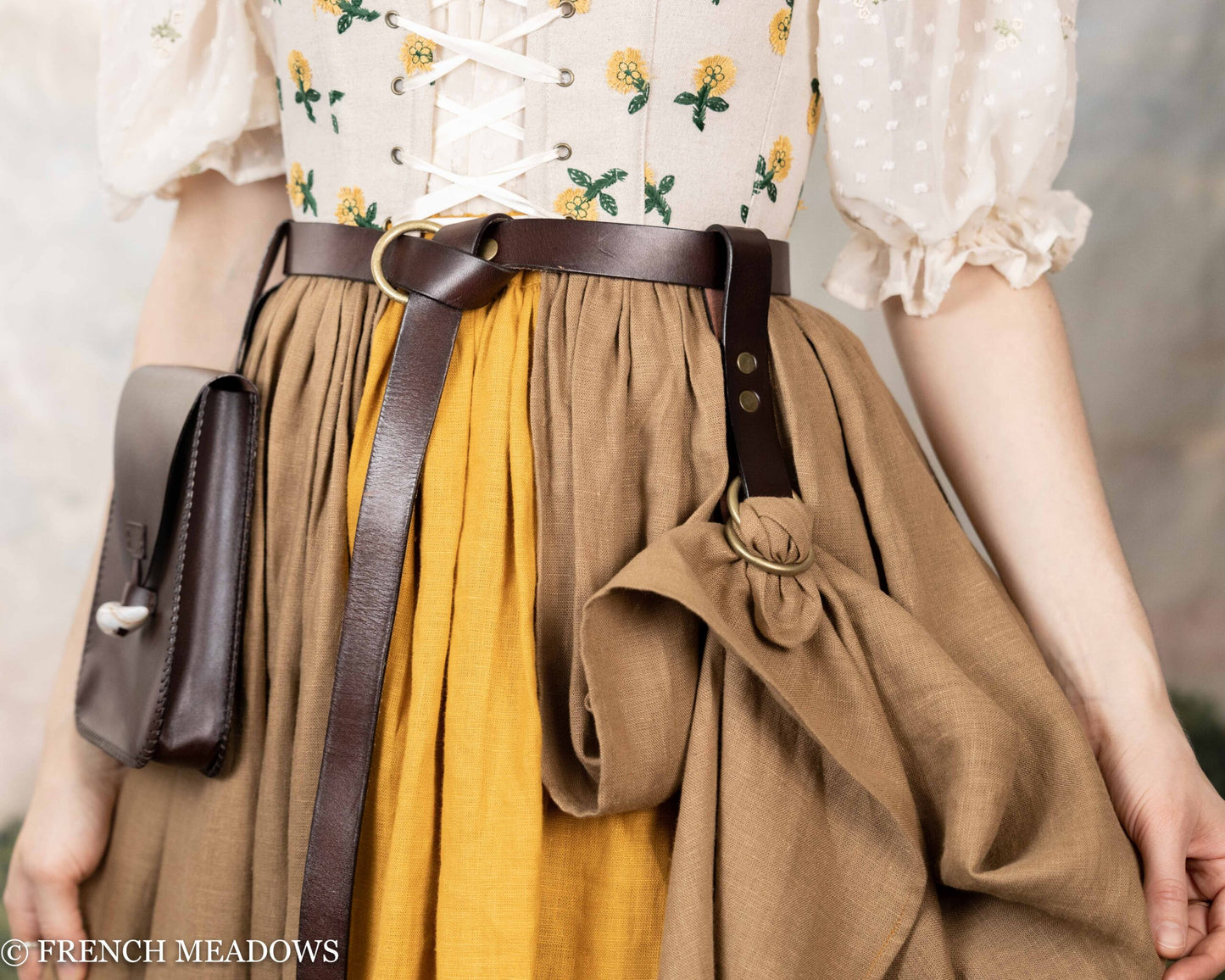 Leather skirt hikes attached to brown belt with medieval dress in beige and yellow, showing practical renaissance wear detail