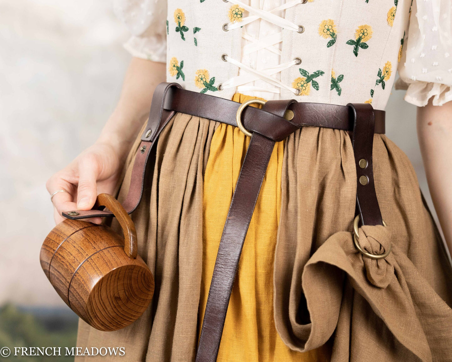 Leather tankard strap on medieval costume with wooden mug, showing brown leather belt attachment and traditional dress details