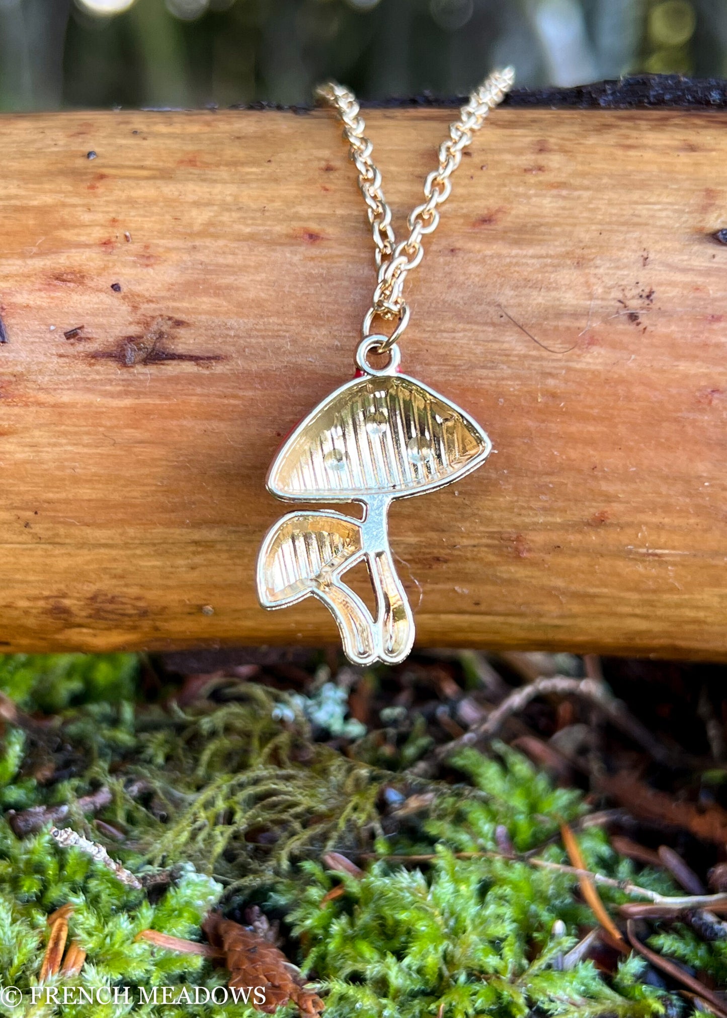 Amanita Mushroom Necklace featuring silver-toned double mushroom pendant on chain, displayed on wood with mossy background