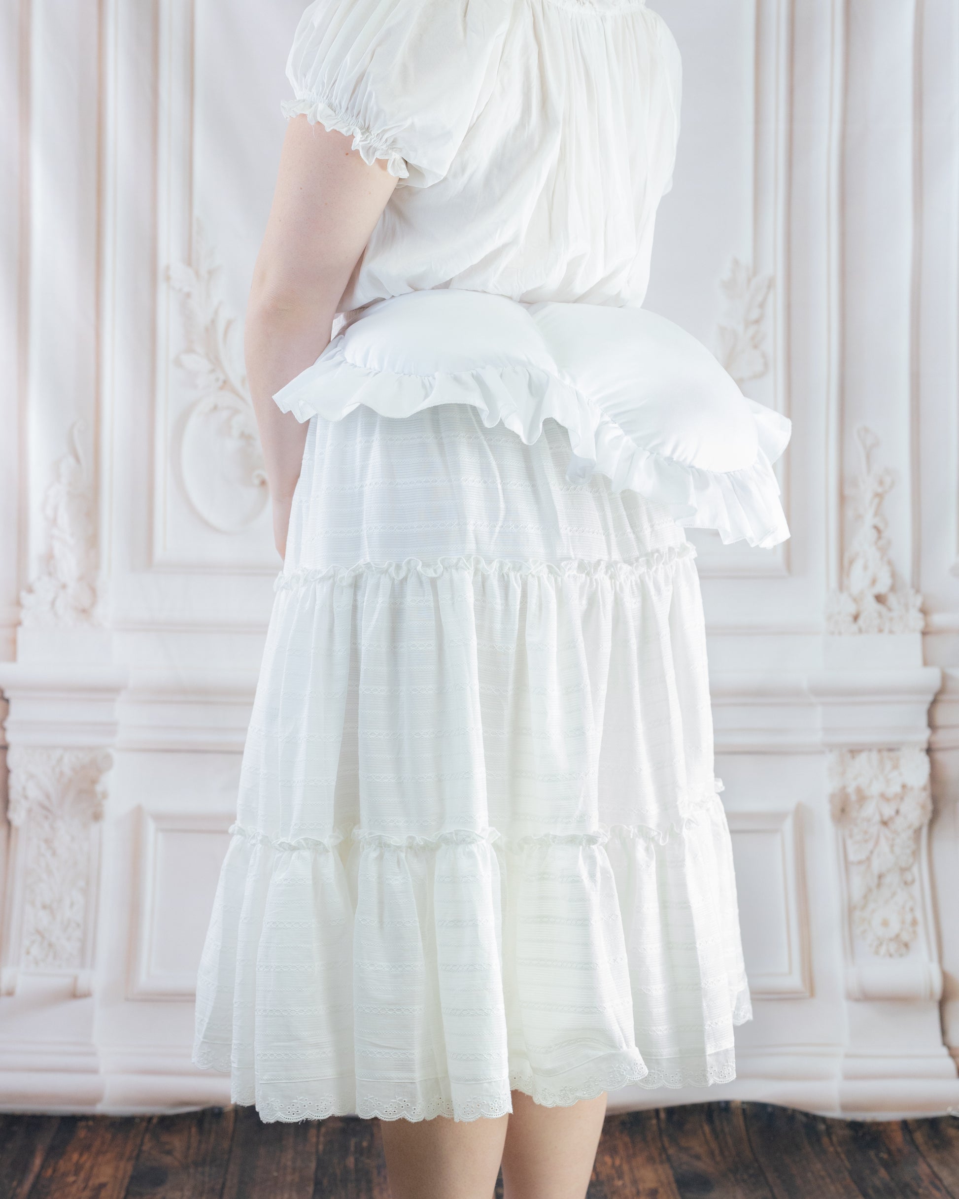 Woman wearing a white skirt with an 18th Century Bustle Pad undergarment adding volume to the back silhouette