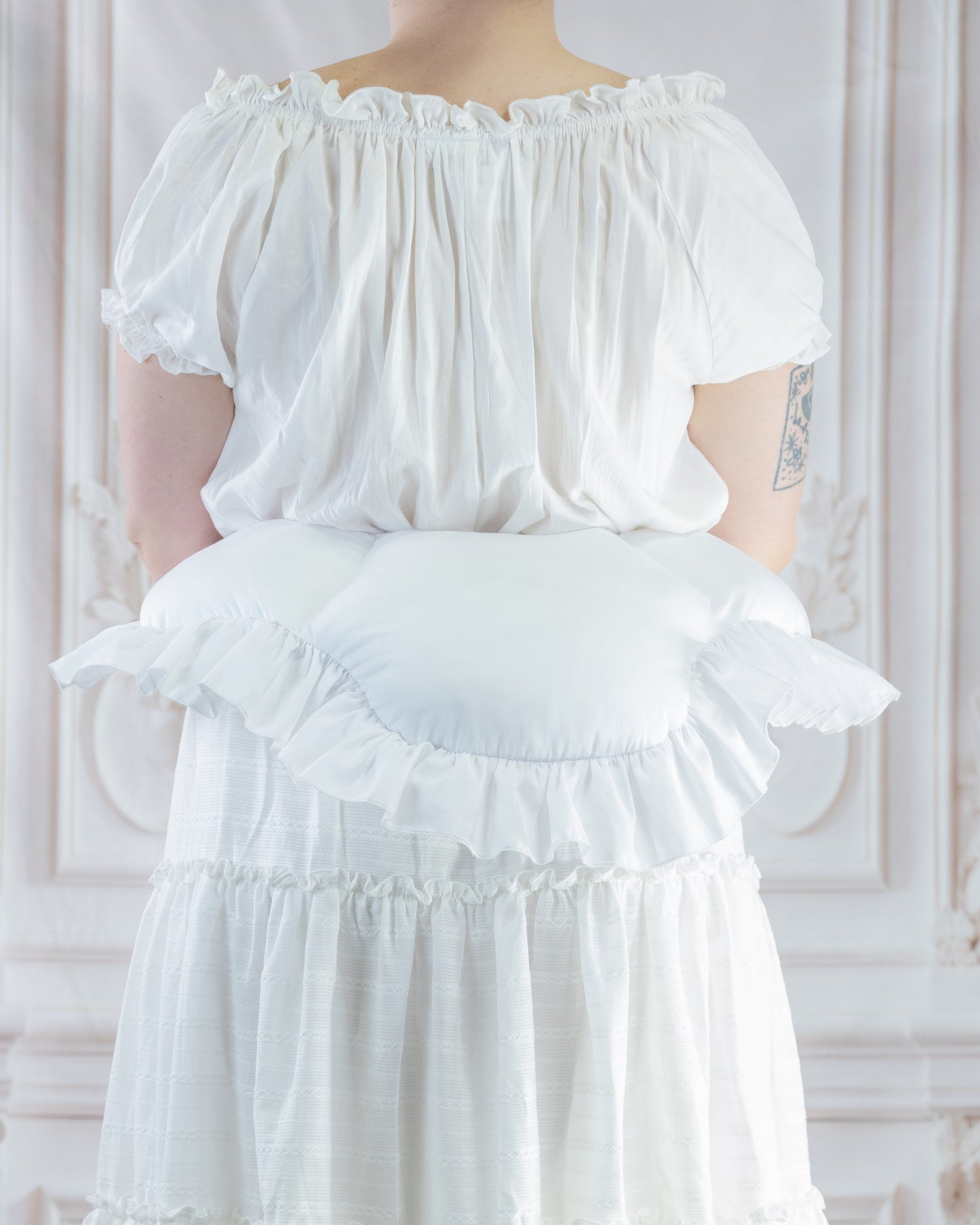 Woman wearing white dress with a ruffled 18th Century Bustle Pad creating a lifted silhouette from the back