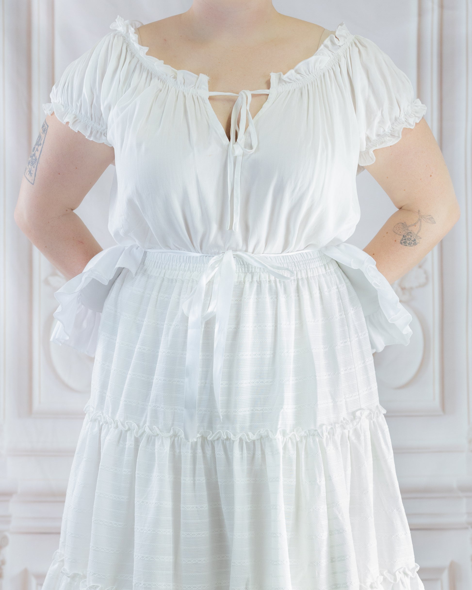 Person wearing a white dress with a Bustle Pad underneath to create a lifted, rounded skirt silhouette.