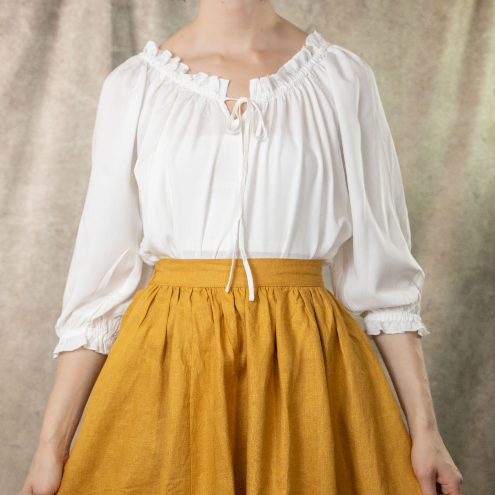 model wearing white cotton peasant blouse with ruffle hem