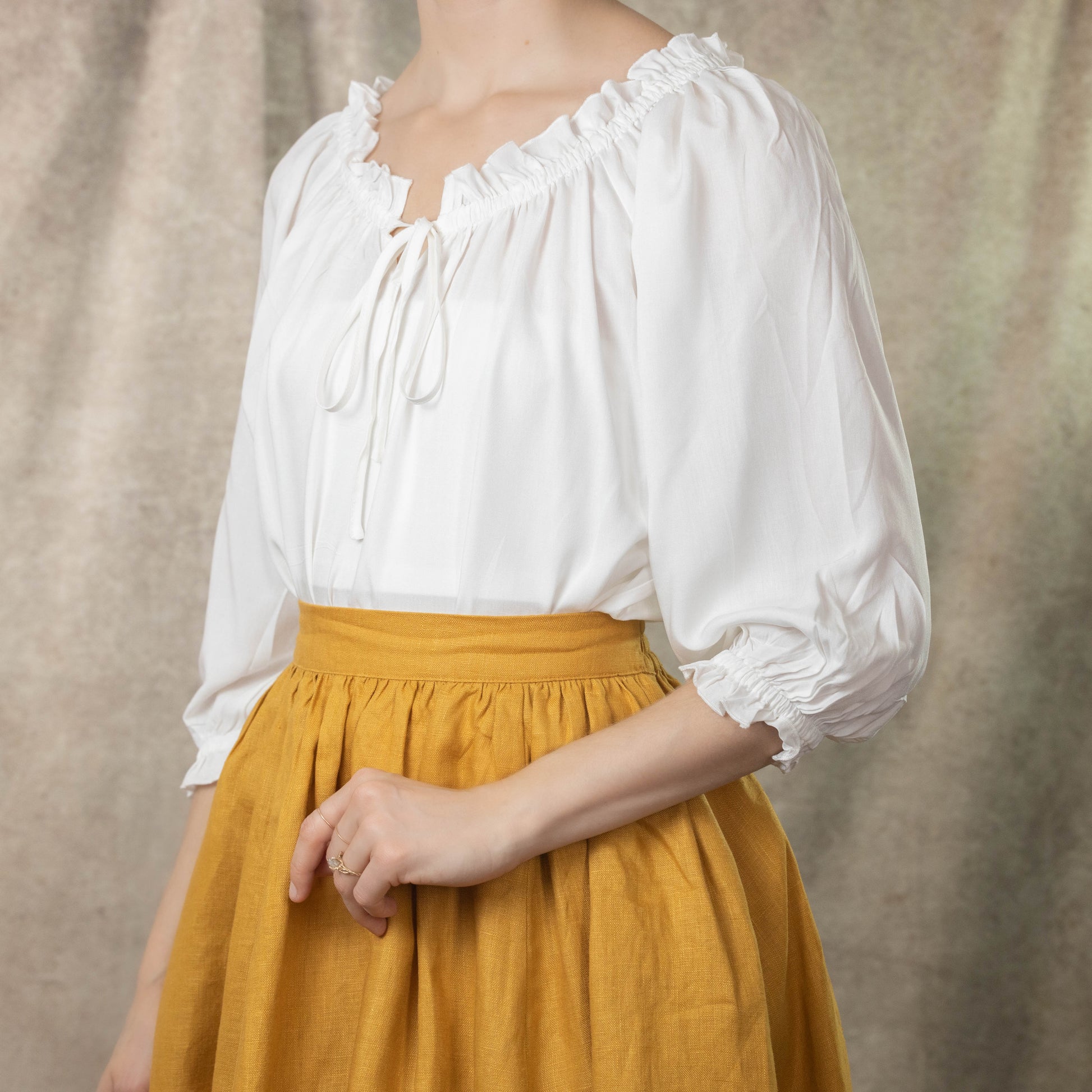 side view of model wearing white blouse showing 3/4 length sleeves