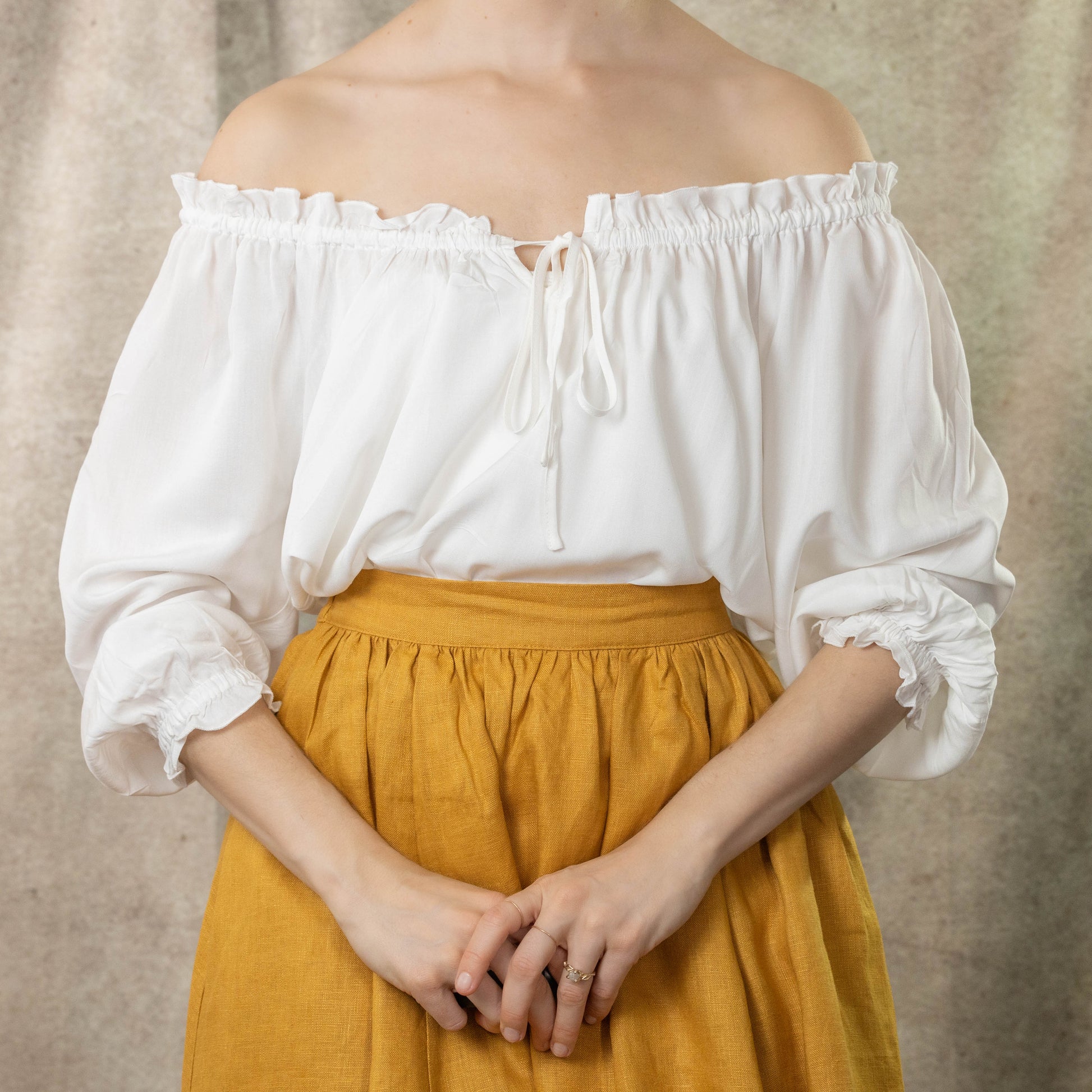 model wearing ivory ruffle sleeve blouse off the shoulders