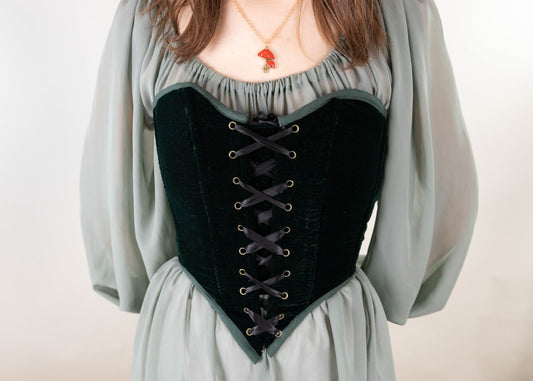 Woman wearing a Handmade Green Velvet Renaissance Corset over a flowing pale green dress with lace-up detail in front