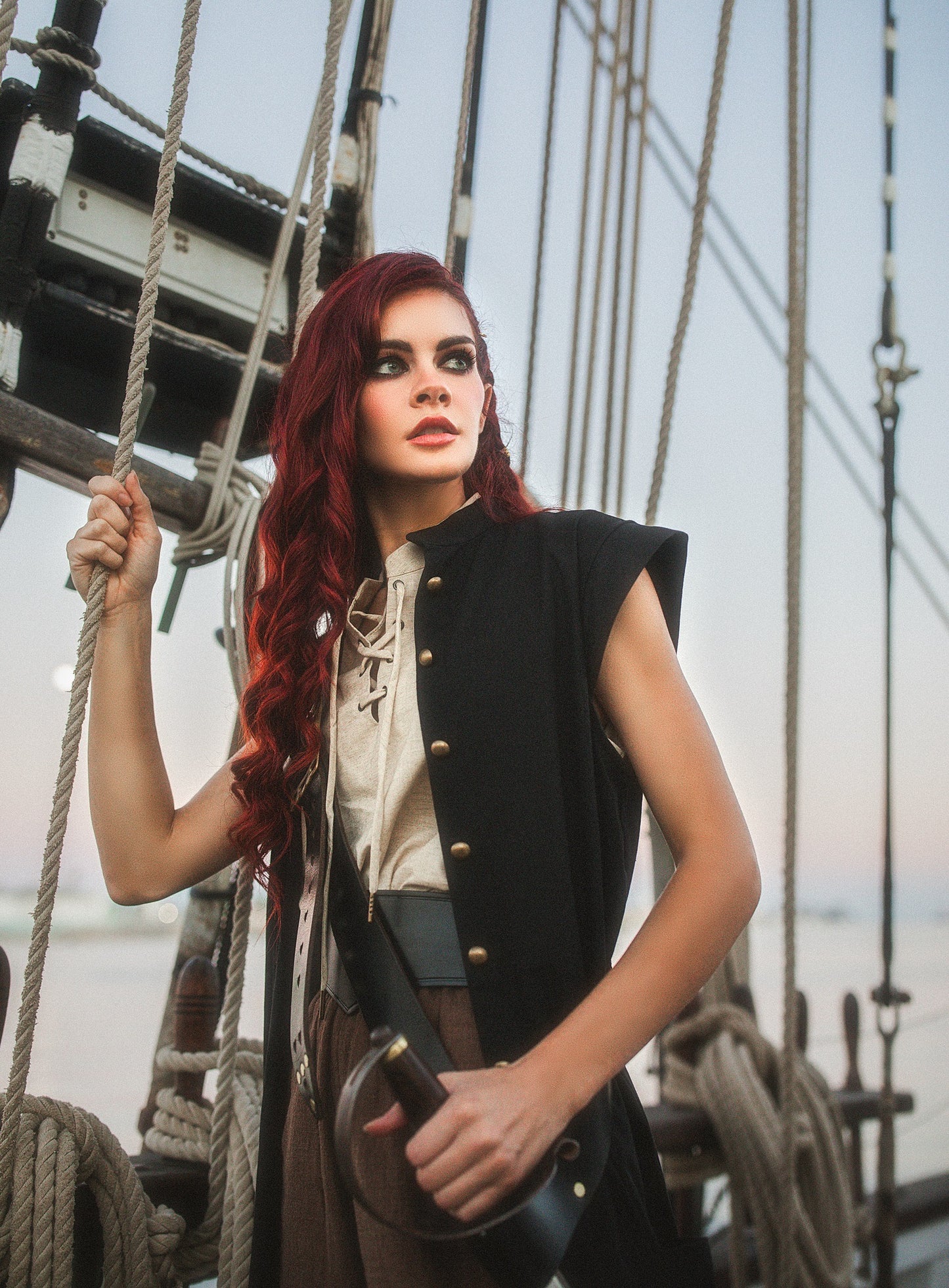 Woman in medieval costume wearing a Wide Leather Waist Belt aboard a ship holding ropes and a sword handle