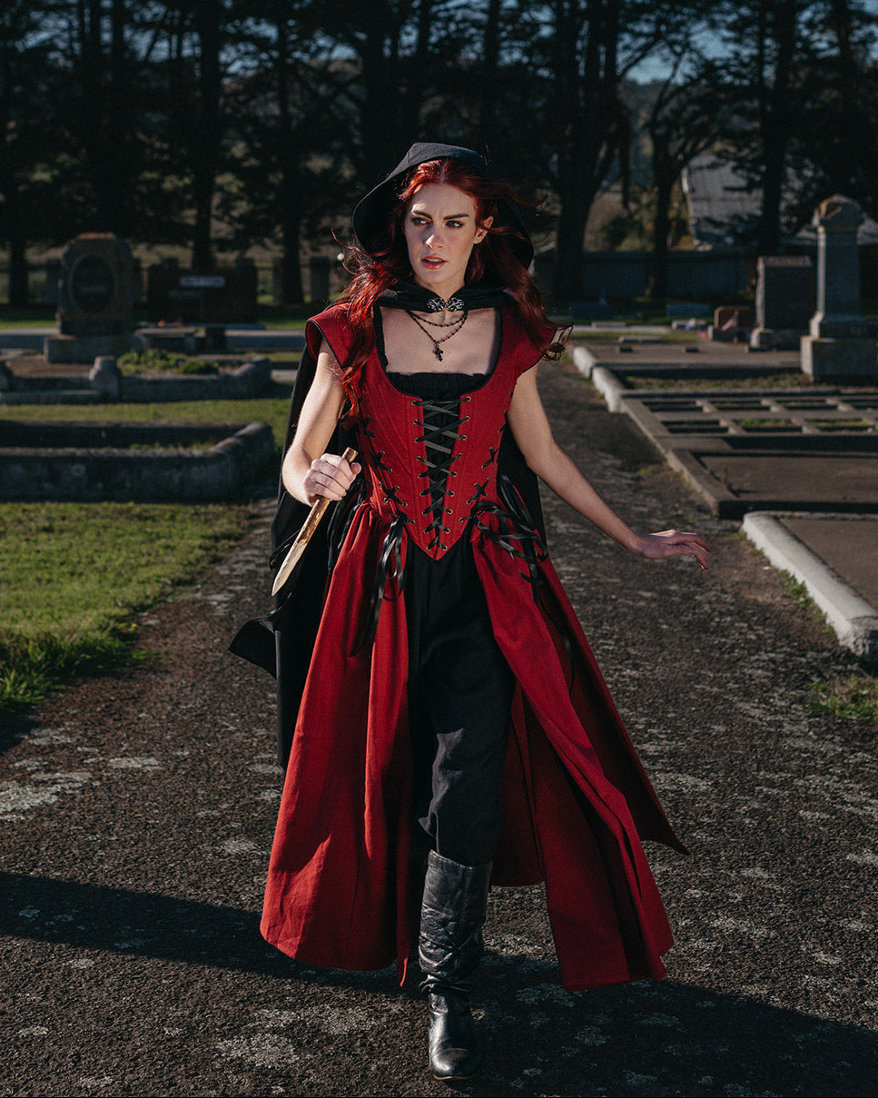 Woman in a graveyard wearing a Red Vampire Slayer Corset Dress with black lacing and a dramatic flowing skirt