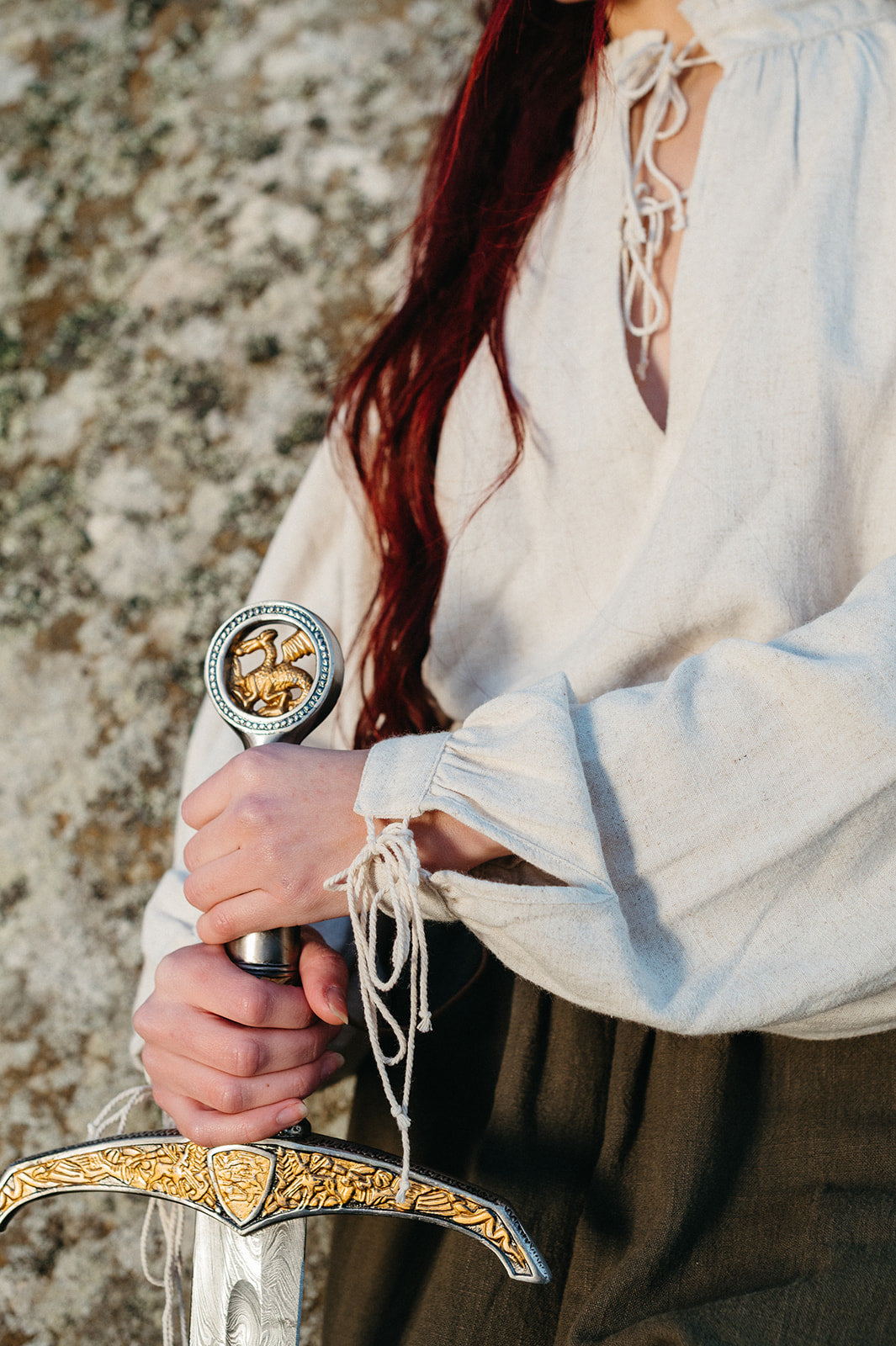 Close-up of hands holding sword, wearing soft linen Borgia Shirt with tied cuffs inspired by Italian Renaissance style