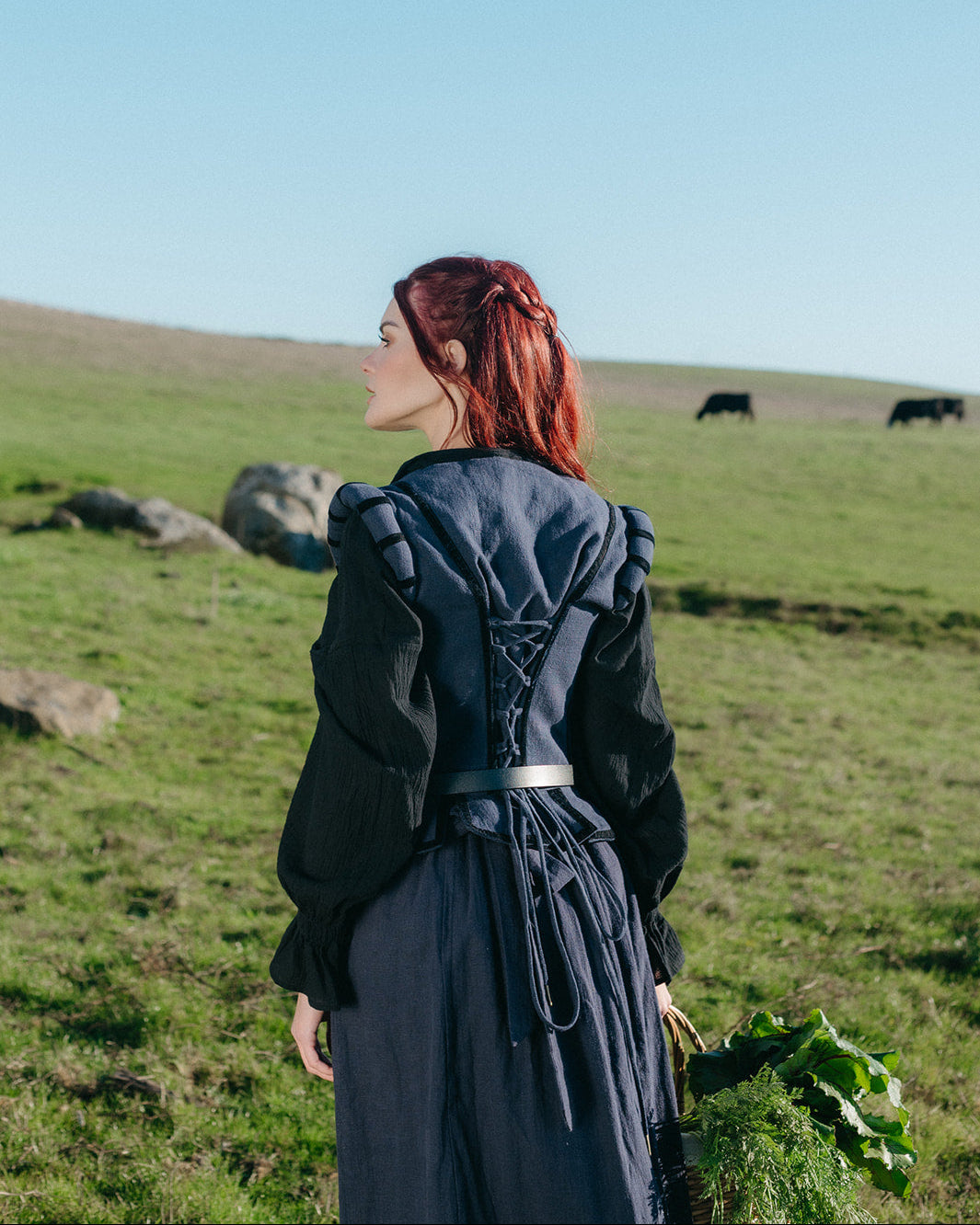 Woman wearing a Navy Tavern Bodice outdoors with lace-up back detail and puffed shoulders in a green field