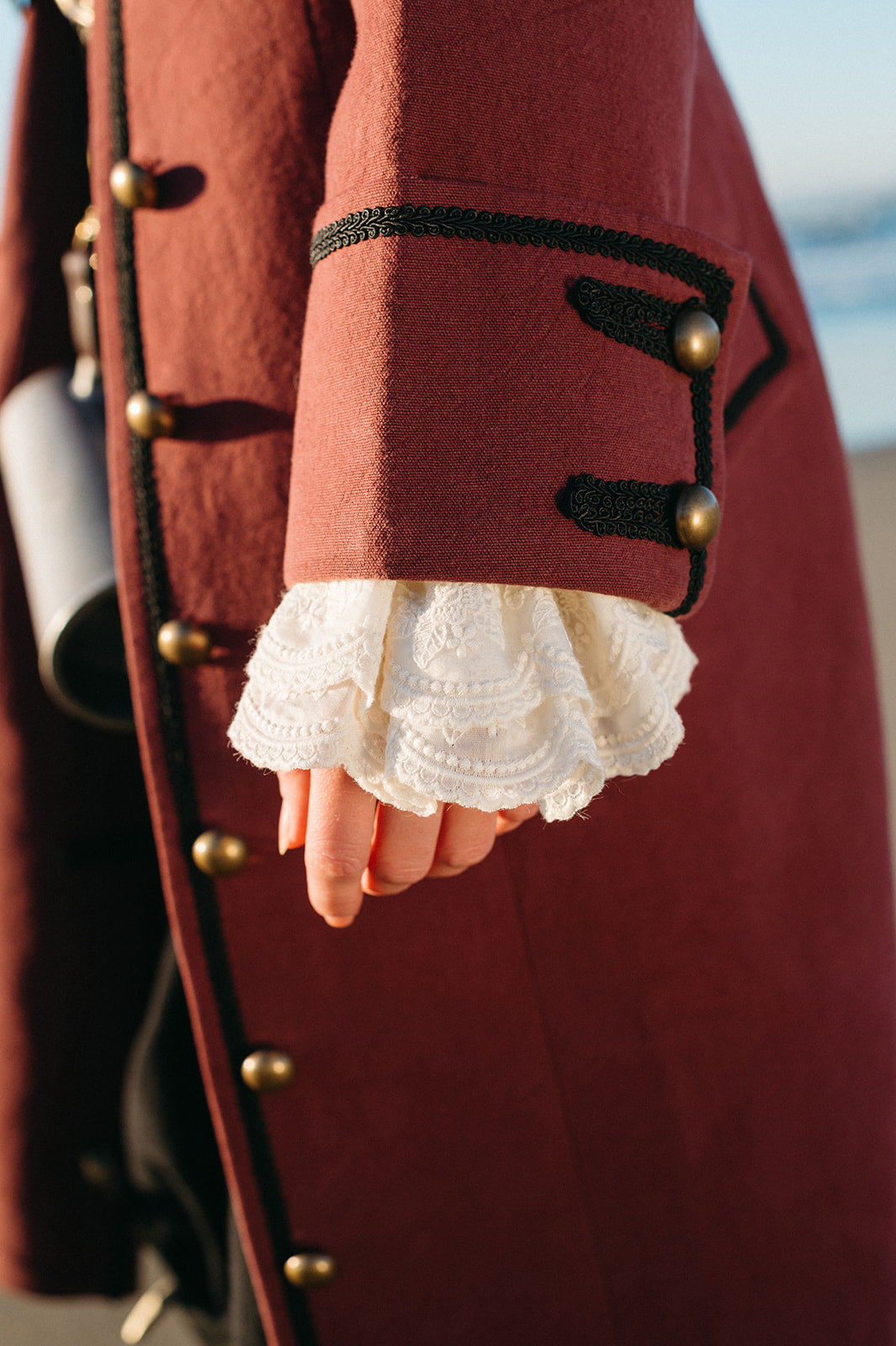 Close-up of sleeve detail on the Pirate Captain's Coat featuring brass buttons and white lace cuff trim