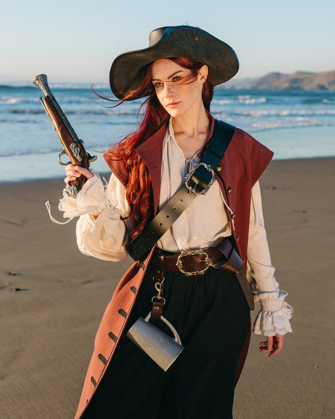Woman dressed as pirate on beach wearing Leather Pirate Belt with large buckle and accessories at sunset