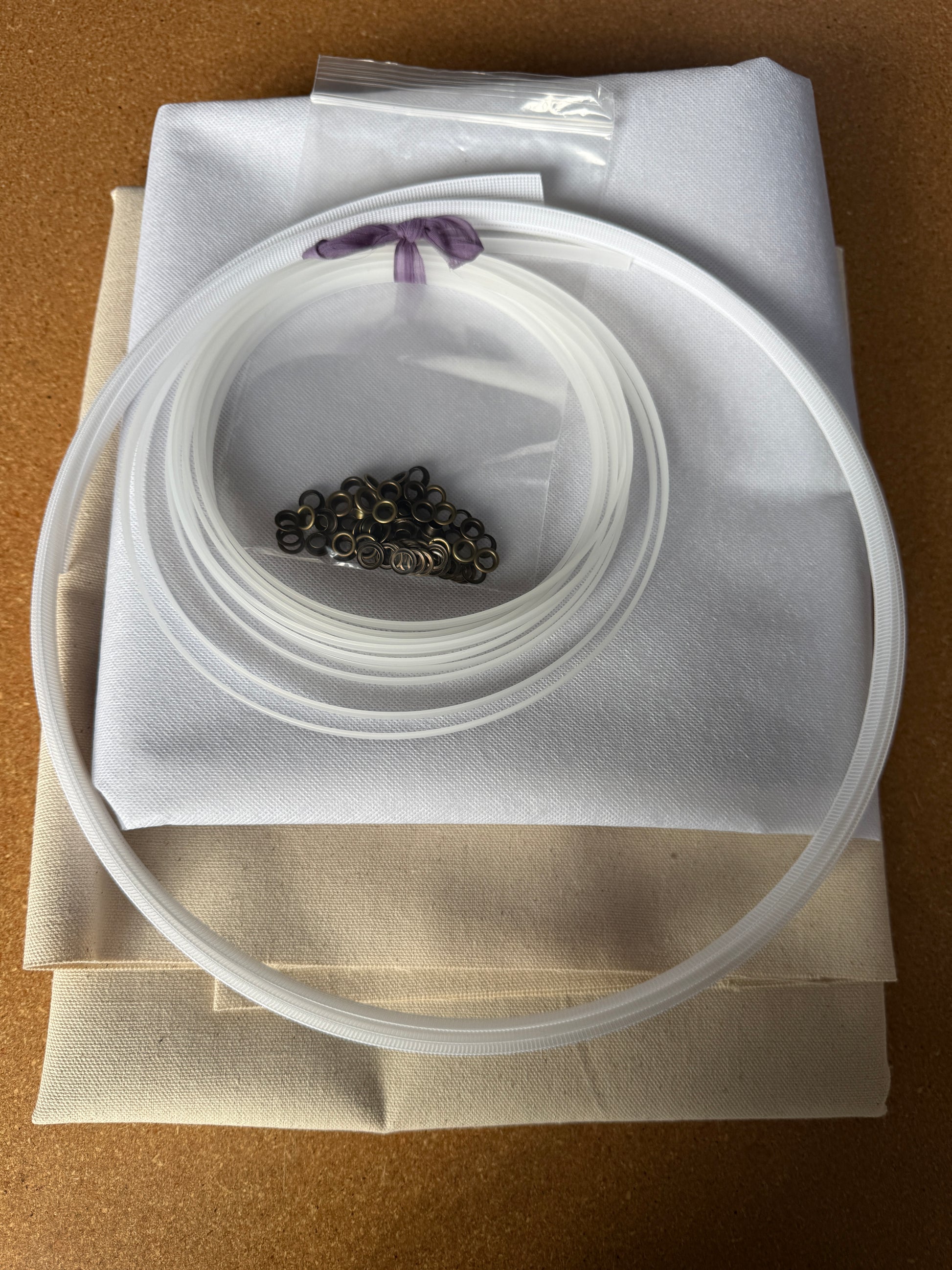 Corset Making Materials Kit with cotton canvas, fusible interfacing, plastic boning, rigiline, and bronze grommets on fabric sheets.