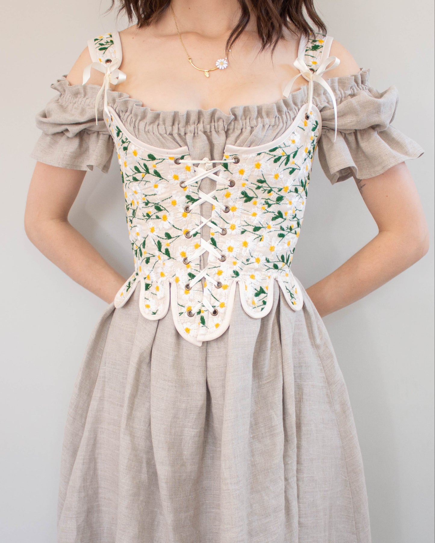 Woman wearing 18th Century Stays Corset Sewing Pattern with floral embroidery and front lacing detail over beige dress