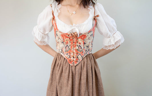 Woman wearing a vintage-style outfit featuring a Handmade Abstract Red Underbust Corset with lace detailing and puffed sleeves