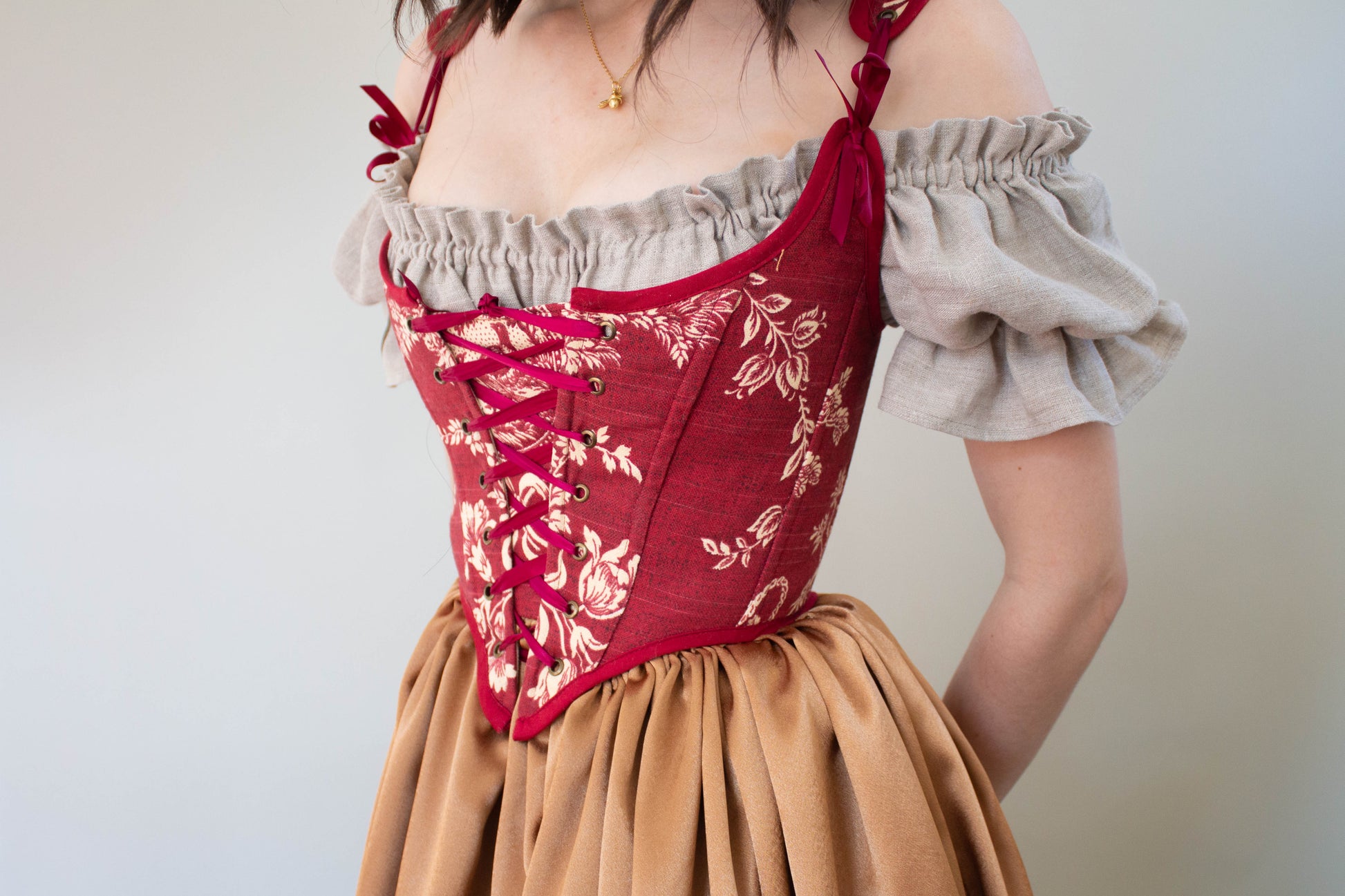 Close-up of a model wearing a Handmade Dark Red Toile Corset with delicate floral pattern and lace-up front.