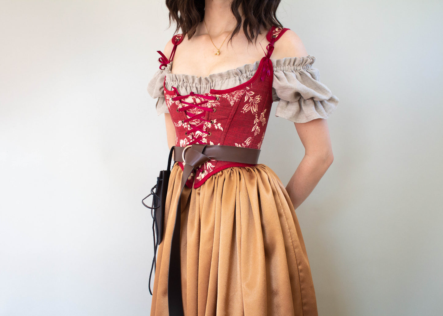 Woman wearing a Handmade Dark Red Toile Corset with beige blouse and mustard skirt against a neutral background