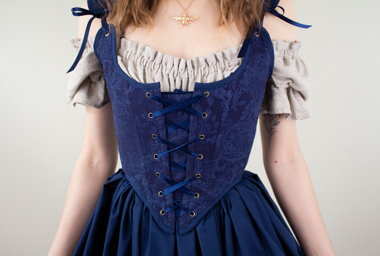 Woman wearing a Handmade Navy Blue Embroidered Floral Corset with lace-up front over an off-shoulder blouse
