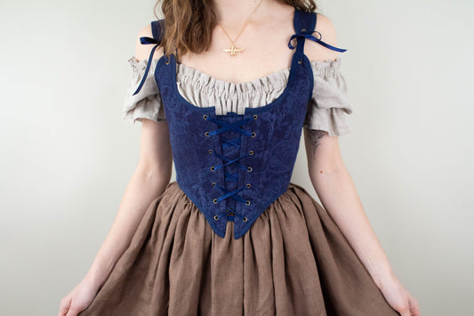 Woman wearing Handmade Navy Blue Embroidered Floral Corset with lace-up front and tied shoulder straps over off-shoulder blouse
