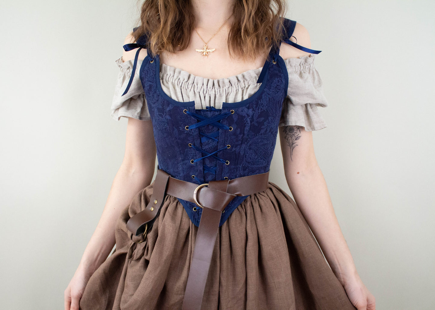 Woman wearing a Handmade Navy Blue Embroidered Floral Corset with a beige blouse and brown skirt, styled with a belt