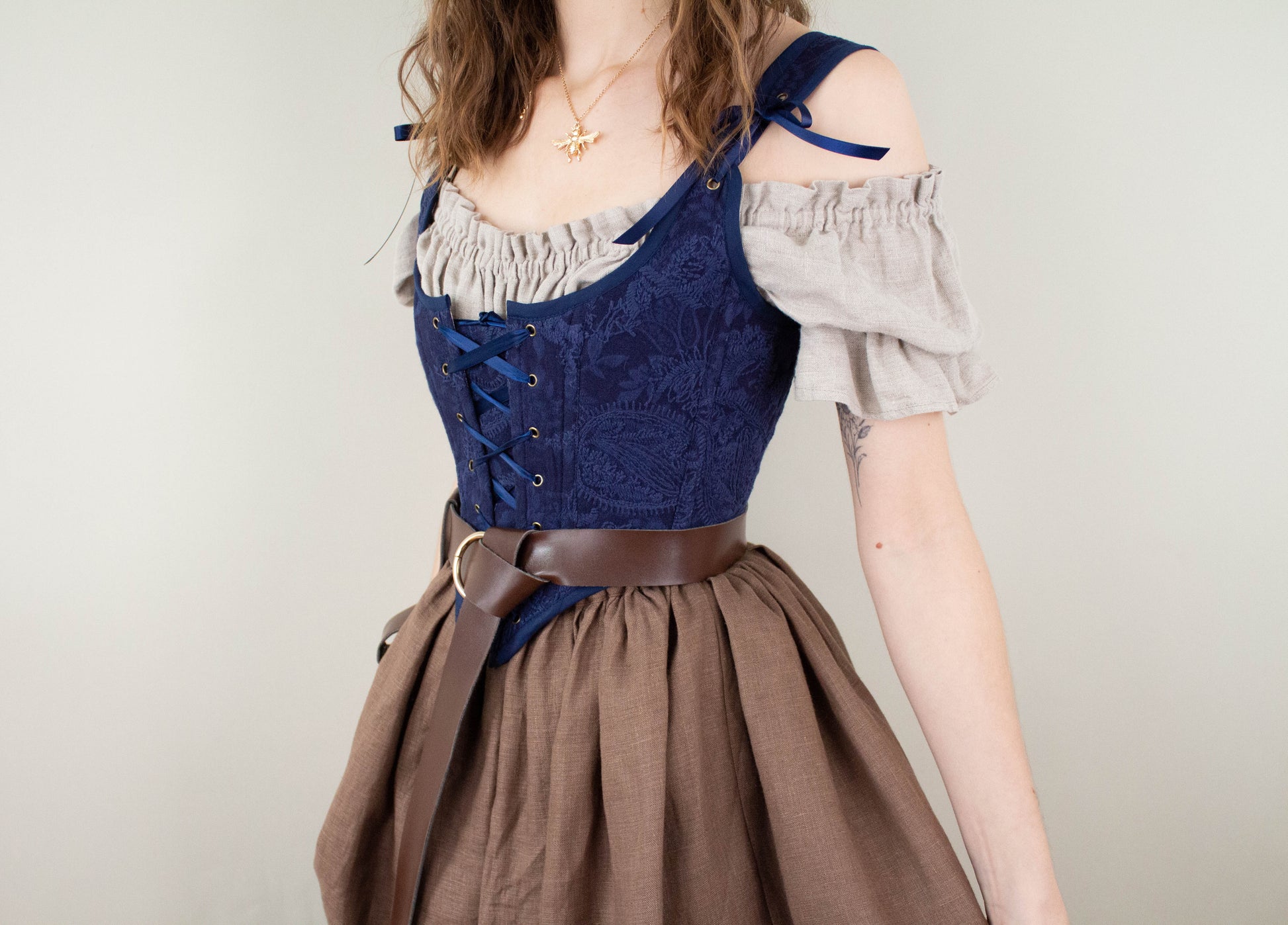 Woman wearing a Handmade Navy Blue Embroidered Floral Corset over an off-shoulder blouse with a brown skirt and belt